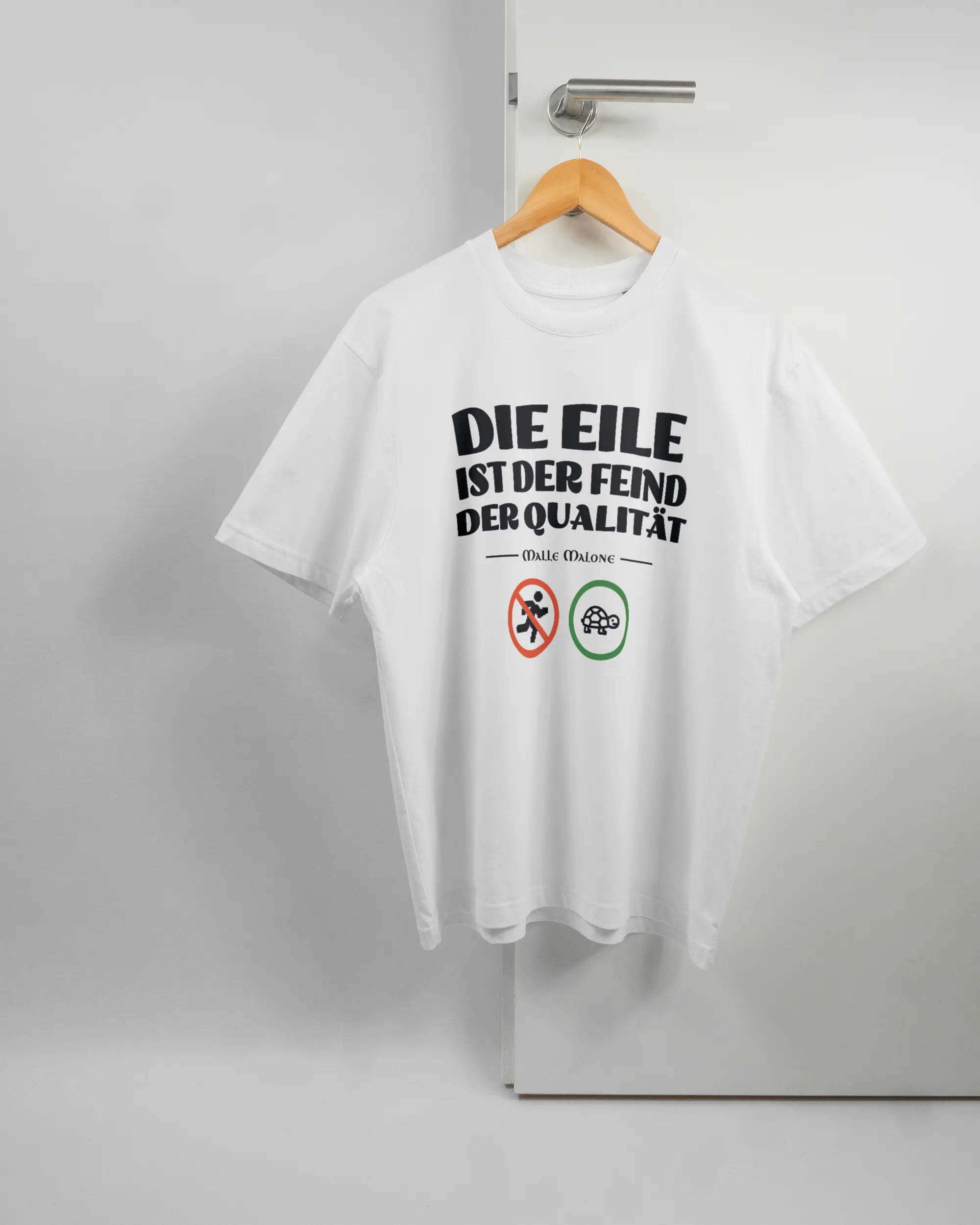 Vorderseite des Basic Unisex T-Shirt Oversized von Maondo mit dem Design Keine Eile in der Farbe White und in der Größe S auf einem Bügel an der Türklinke aufgehängt