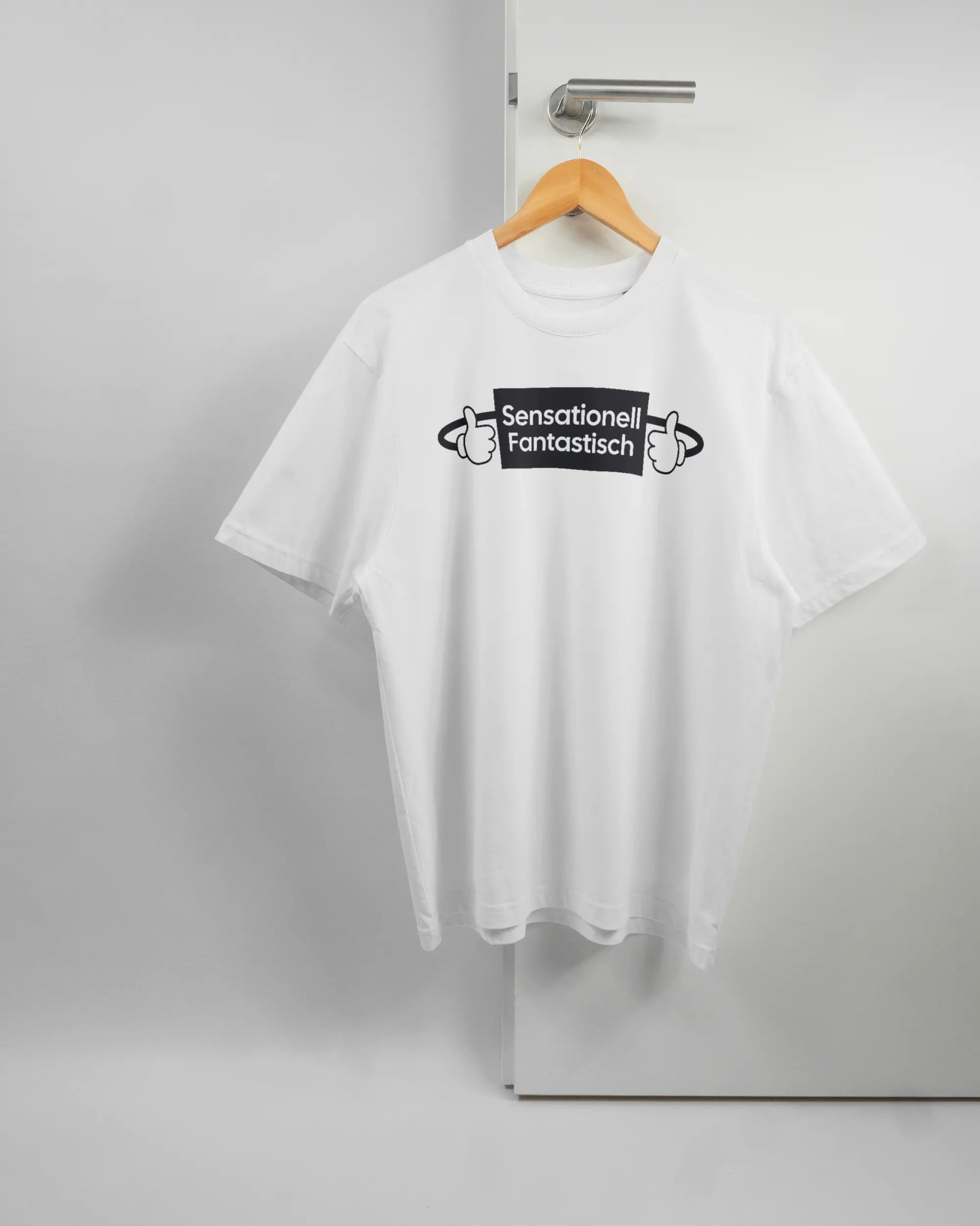Vorderseite des Basic Unisex T-Shirt Oversized von Maondo mit dem Design Fantastisch in der Farbe White und in der Größe S auf einem Bügel an der Türklinke aufgehängt