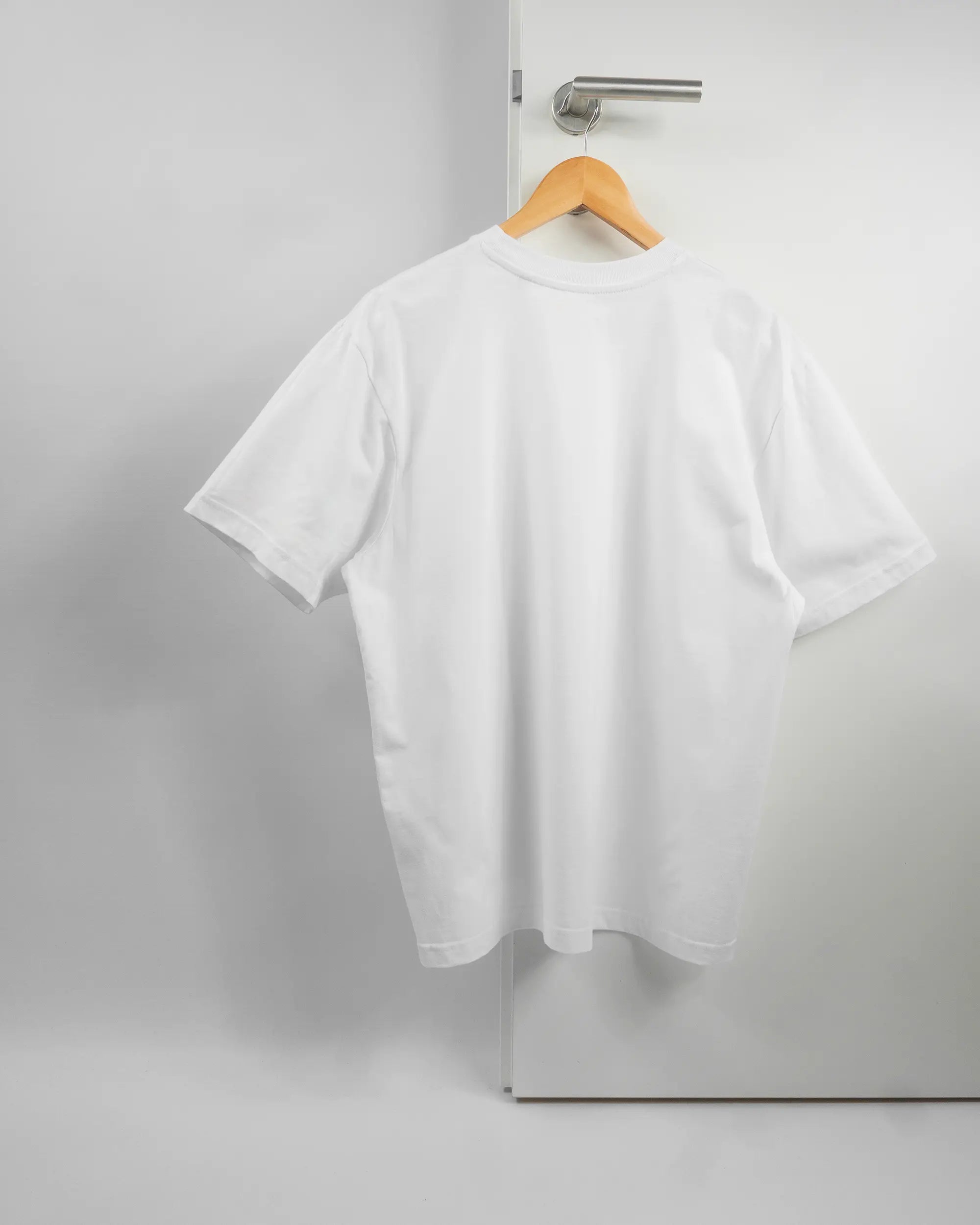 Rückseite des Basic Unisex T-Shirt Oversized von Maondo ohne Motiv in der Farbe White und in der Größe S auf einem Bügel an der Türklinke aufgehängt