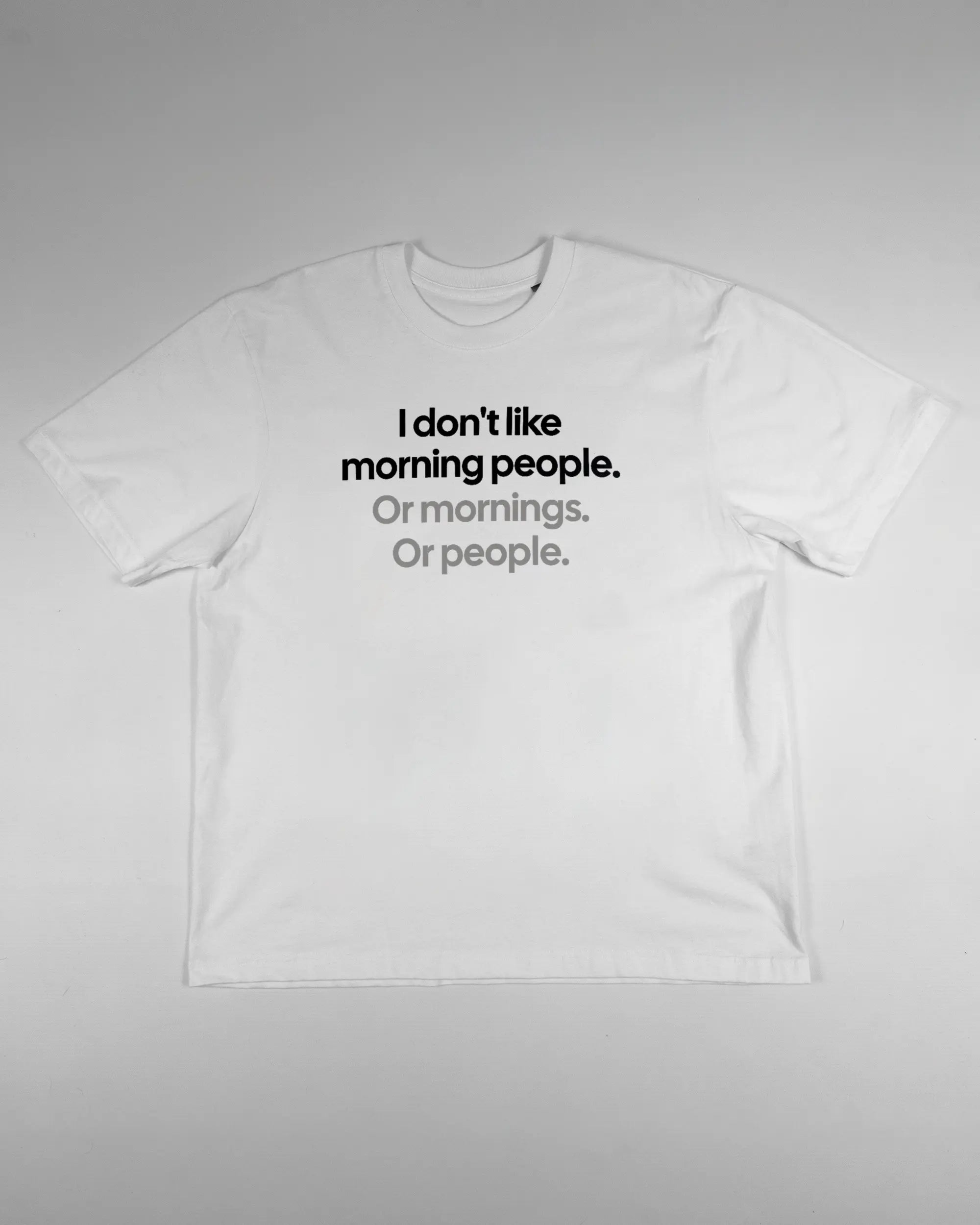 Vorderseite des Basic Unisex T-Shirt Oversized von Maondo mit dem Design Morning Person in der Farbe White und in der Größe S flach auf den Boden gelegt