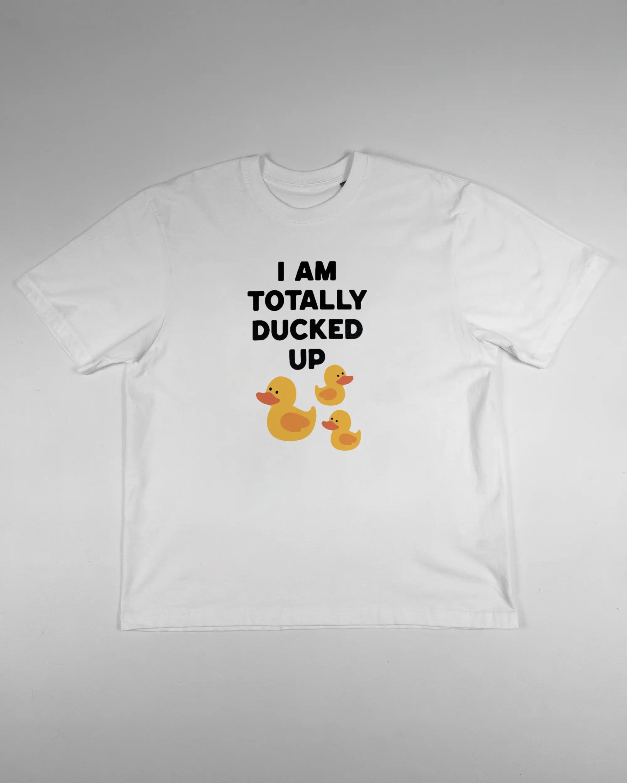 Vorderseite des Basic Unisex T-Shirt Oversized von Maondo mit dem Design Ducked Up in der Farbe White und in der Größe S flach auf den Boden gelegt