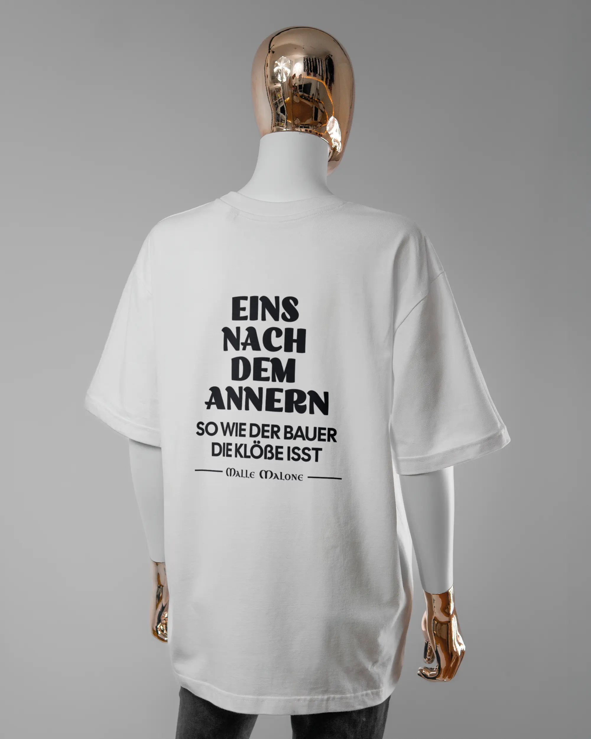 Rückseite des Basic Unisex T-Shirt Oversized von Maondo mit dem Design Eins nach dem Annern in der Farbe White und in der Größe S getragen von einer femininen Puppe