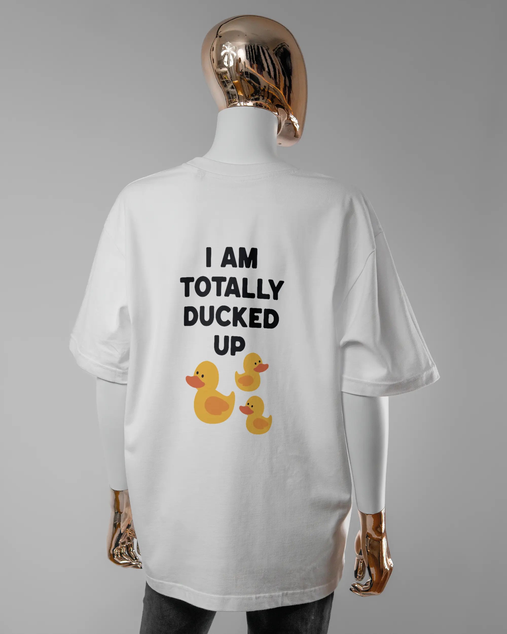 Rückseite des Basic Unisex T-Shirt Oversized von Maondo mit dem Design Ducked Up in der Farbe White und in der Größe S getragen von einer femininen Puppe
