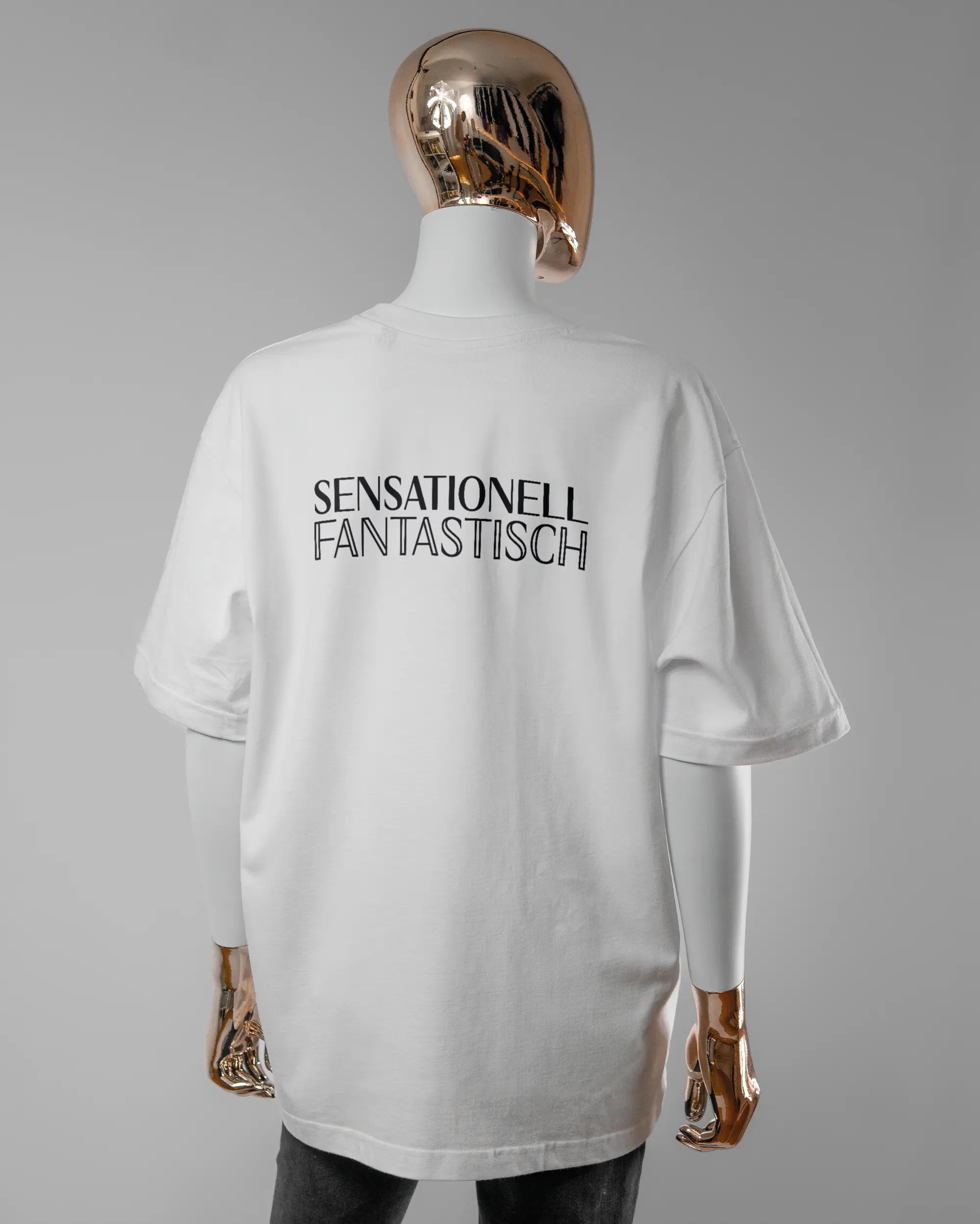 Rückseite des Basic Unisex T-Shirt Oversized von Maondo mit dem Design Sensationell in der Farbe White und in der Größe S getragen von einer femininen Puppe