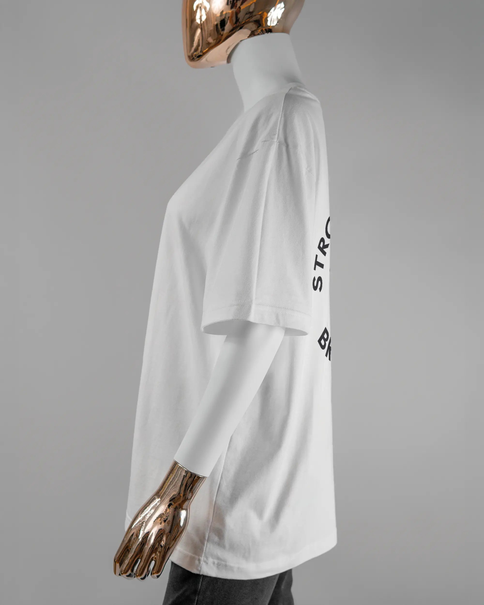 Seitenansicht des Basic Unisex T-Shirt Oversized von Maondo mit dem Design Brocco-Lee hinten in der Farbe White und in der Größe S getragen von einer femininen Puppe