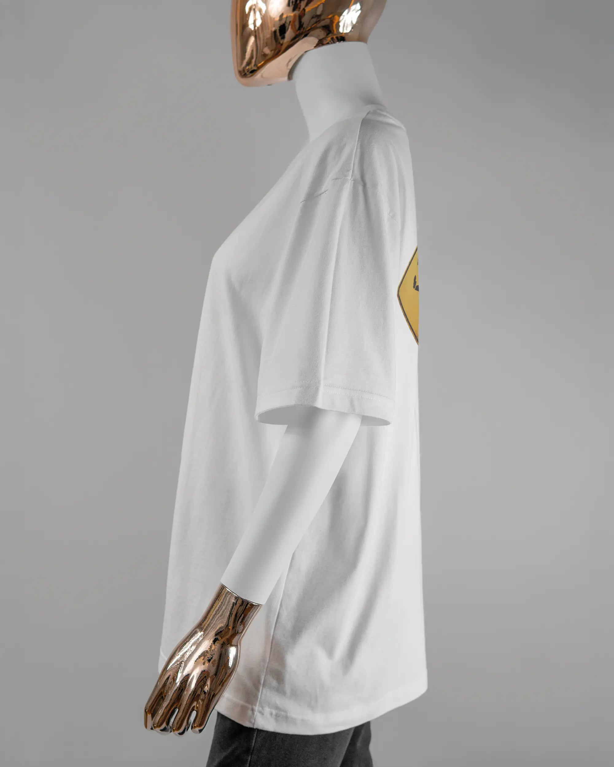 Seitenansicht des Basic Unisex T-Shirt Oversized von Maondo mit dem Design Schutzschild hinten in der Farbe White und in der Größe S getragen von einer femininen Puppe