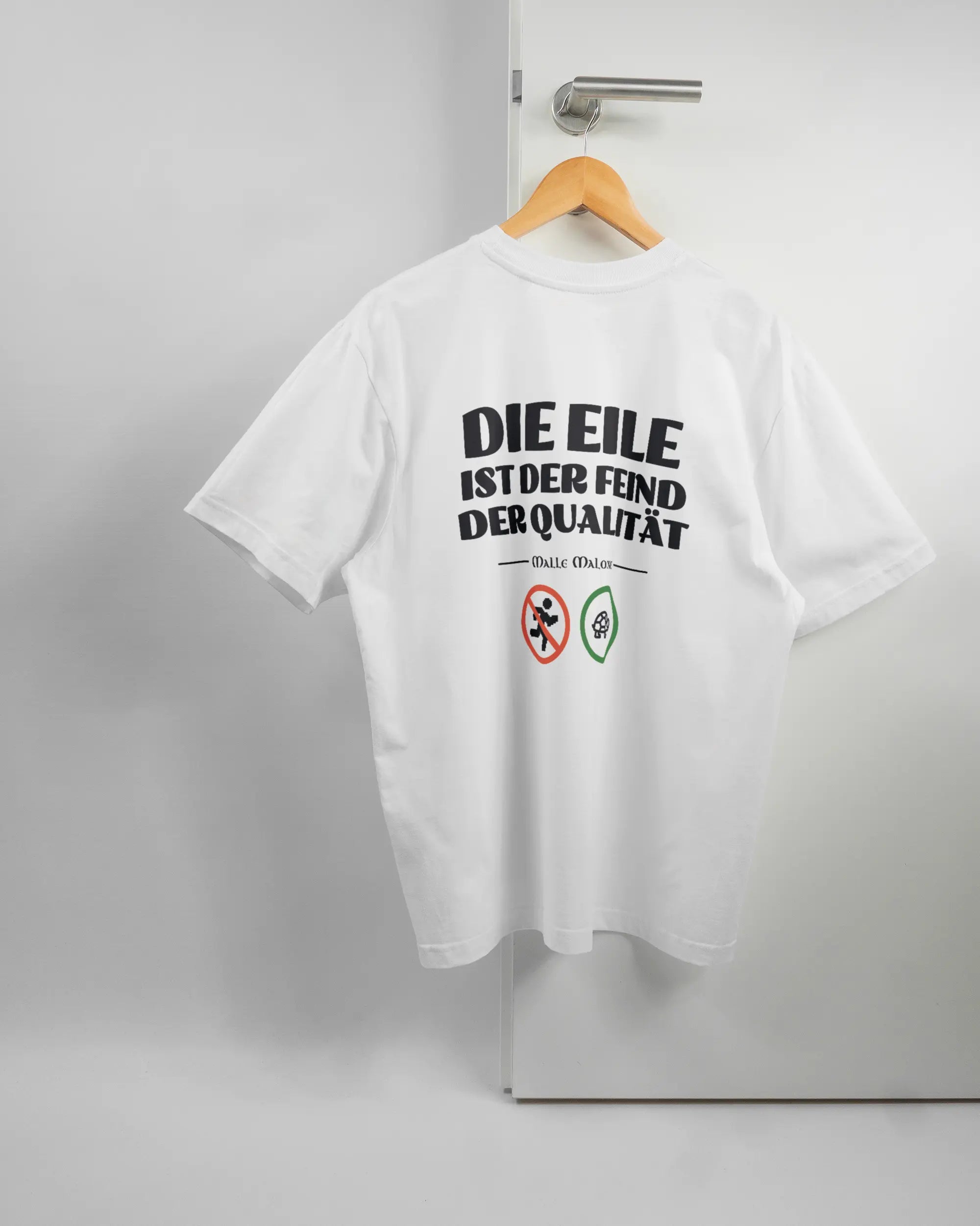 Rückseite des Basic Unisex T-Shirt Oversized von Maondo mit dem Design Keine Eile in der Farbe White und in der Größe S auf einem Bügel an der Türklinke aufgehängt