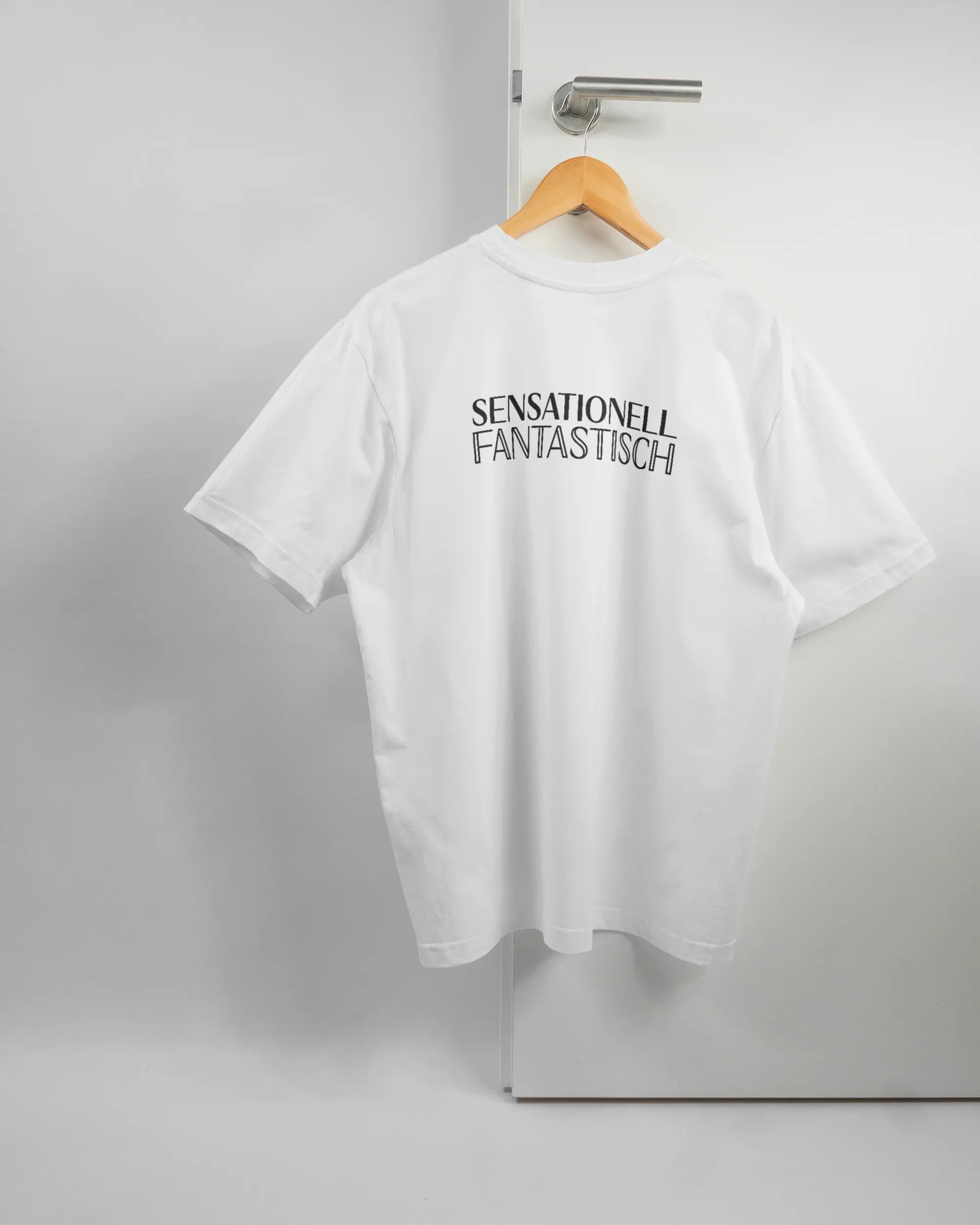 Rückseite des Basic Unisex T-Shirt Oversized von Maondo mit dem Design Sensationell in der Farbe White und in der Größe S auf einem Bügel an der Türklinke aufgehängt