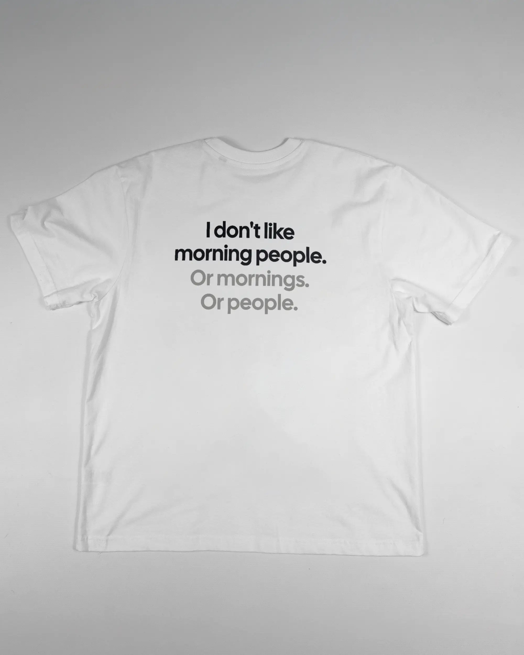 Rückseite des Basic Unisex T-Shirt Oversized von Maondo mit dem Design Morning Person in der Farbe White und in der Größe S flach auf den Boden gelegt