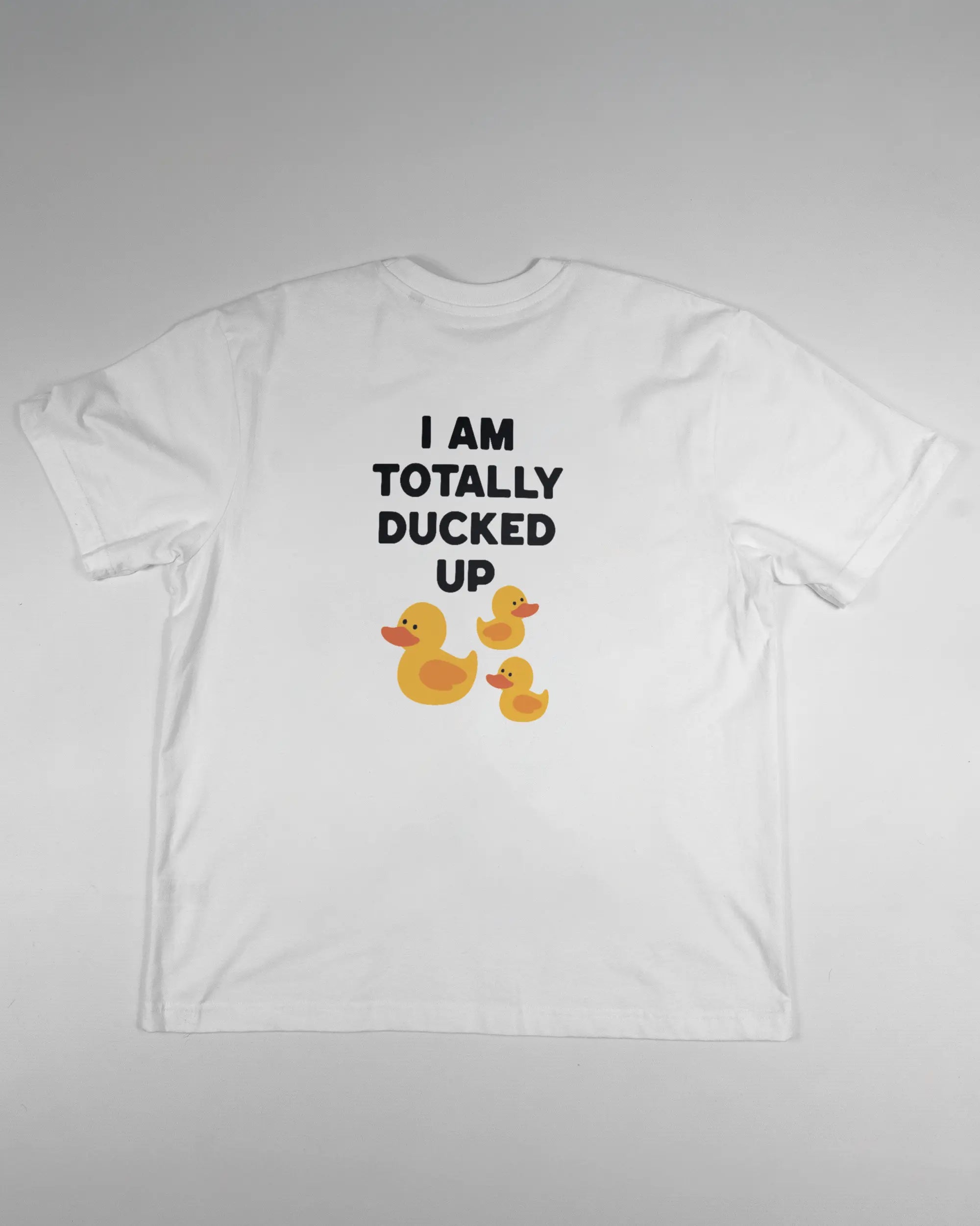 Rückseite des Basic Unisex T-Shirt Oversized von Maondo mit dem Design Ducked Up in der Farbe White und in der Größe S flach auf den Boden gelegt