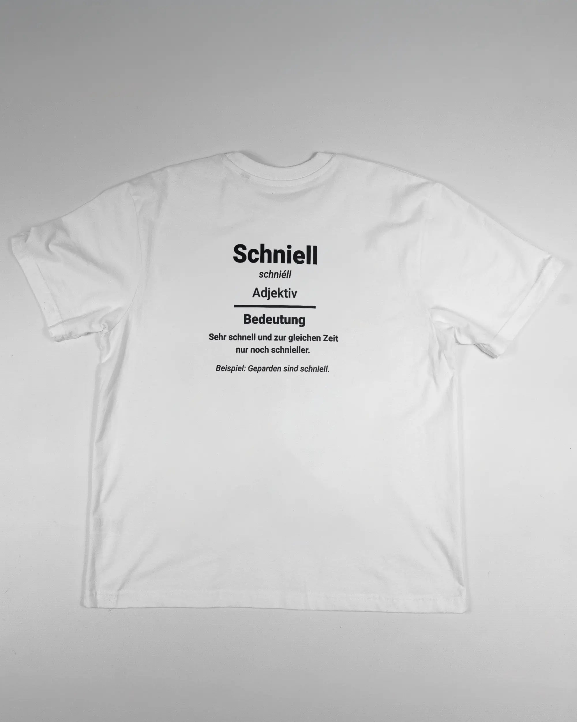 Rückseite des Basic Unisex T-Shirt Oversized von Maondo mit dem Design Schniell in der Farbe White und in der Größe S flach auf den Boden gelegt
