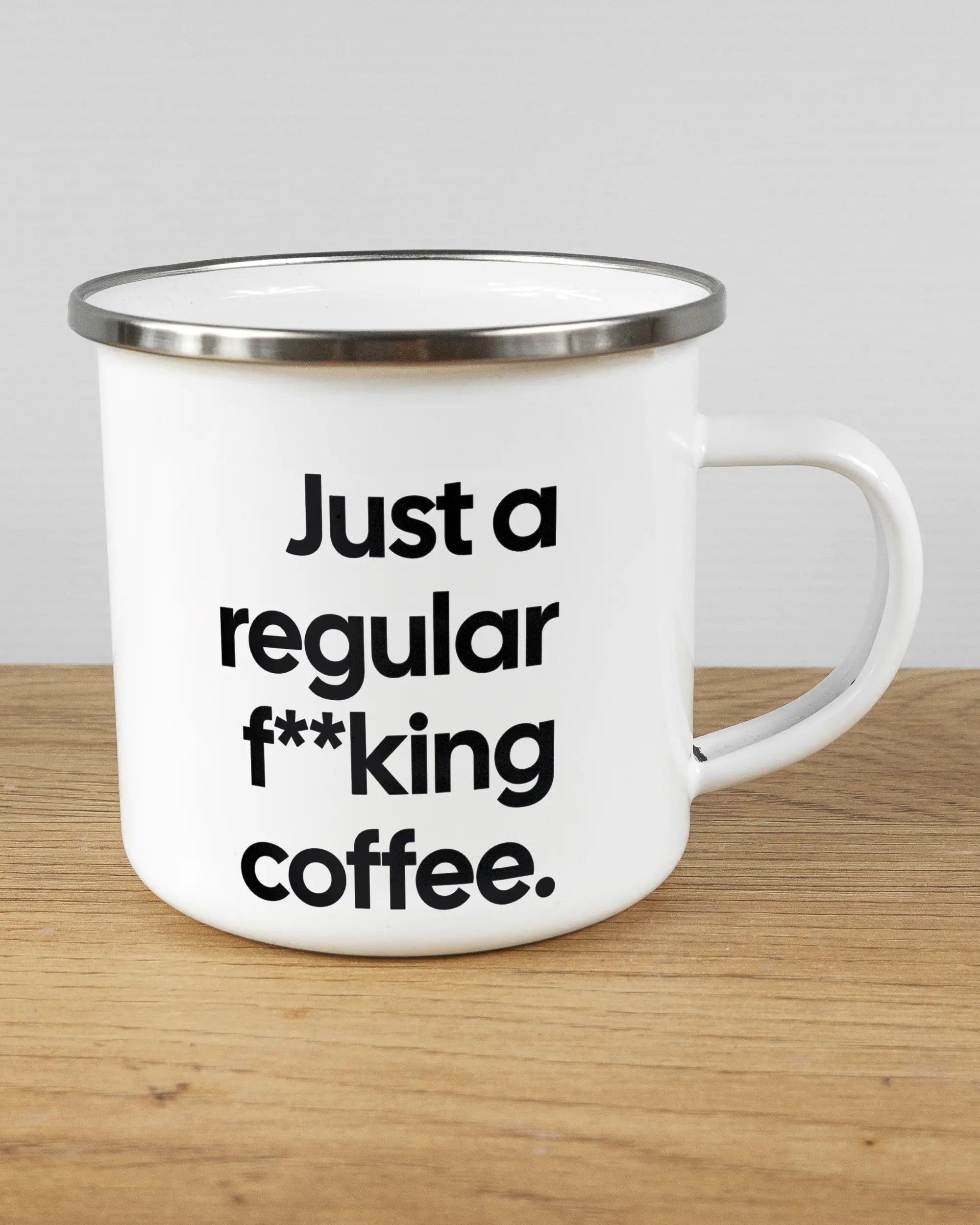 Alternativbild, das die rechte Seite der beidseitig bedruckten Emailletasse von Maondo mit dem Design Regular Coffee in der Farbe White-Silver auf einem Holztisch zeigt