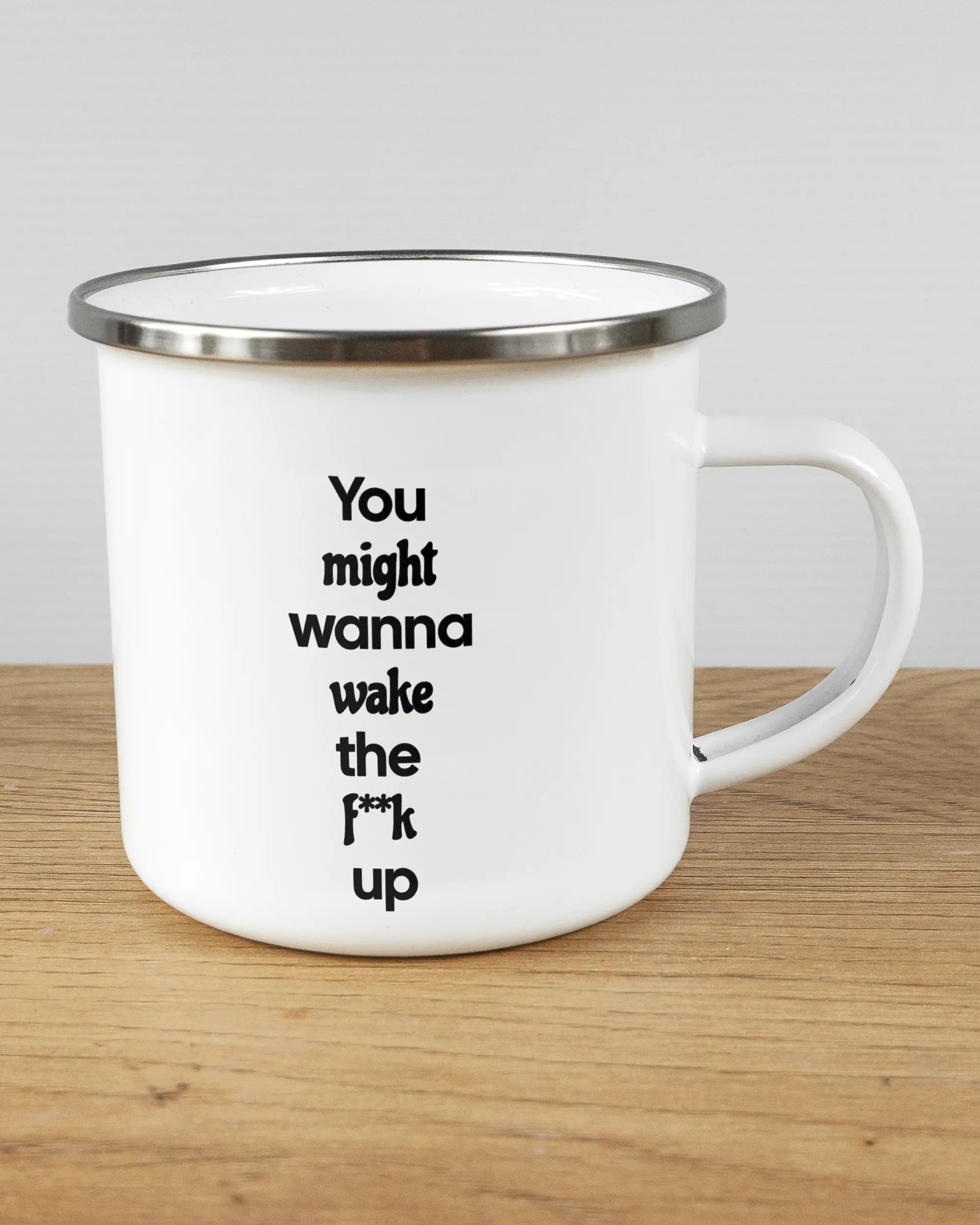 Alternativbild, das die rechte Seite der beidseitig bedruckten Emailletasse von Maondo mit dem Design Wanna Wake in der Farbe White-Silver auf einem Holztisch zeigt