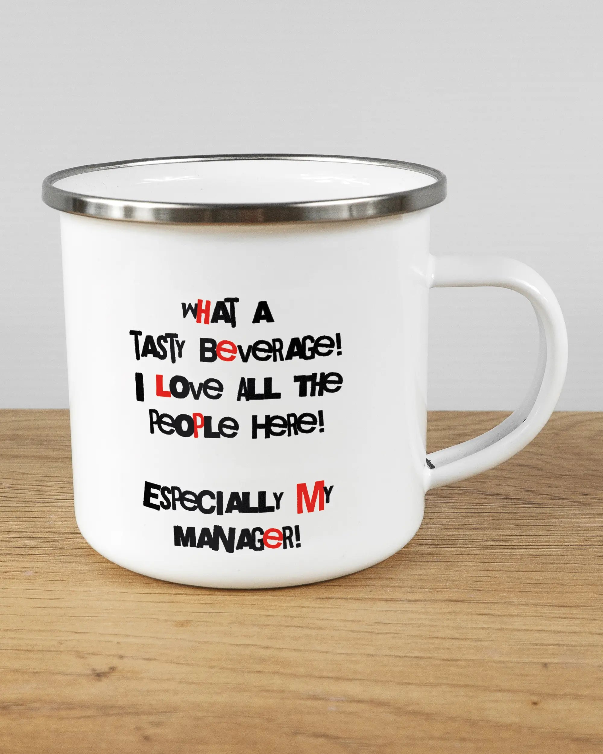 Alternativbild, das die rechte Seite der beidseitig bedruckten Emailletasse von Maondo mit dem Design Help me in der Farbe White-Silver auf einem Holztisch zeigt