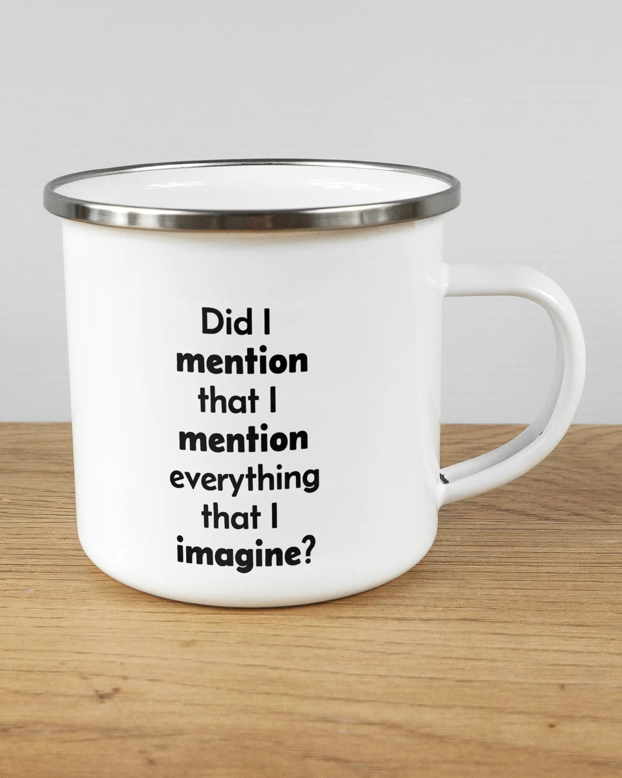 Alternativbild, das die rechte Seite der beidseitig bedruckten Emailletasse von Maondo mit dem Design Did I mention in der Farbe White-Silver auf einem Holztisch zeigt