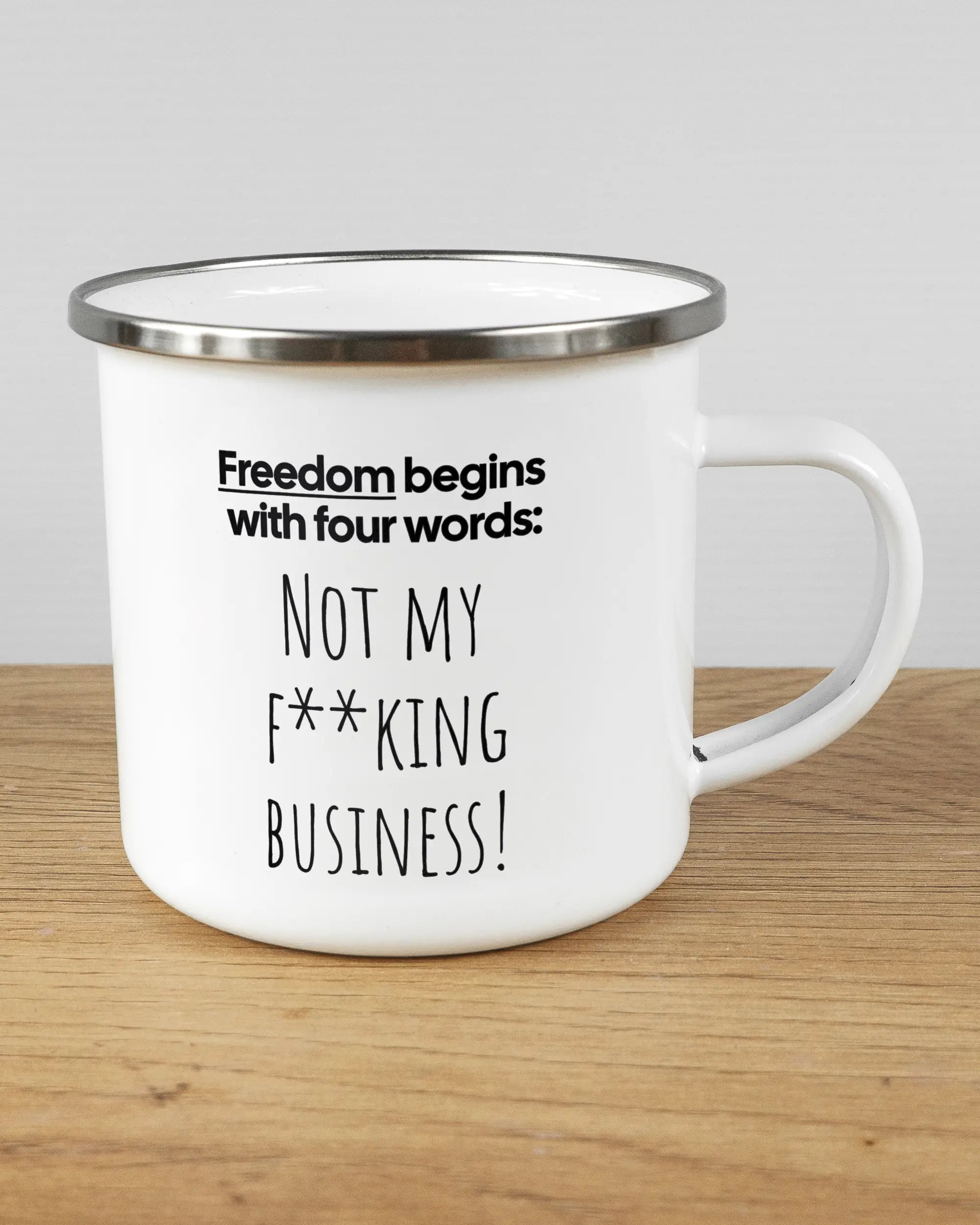 Alternativbild, das die rechte Seite der beidseitig bedruckten Emailletasse von Maondo mit dem Design 4 Freedom in der Farbe White-Silver auf einem Holztisch zeigt