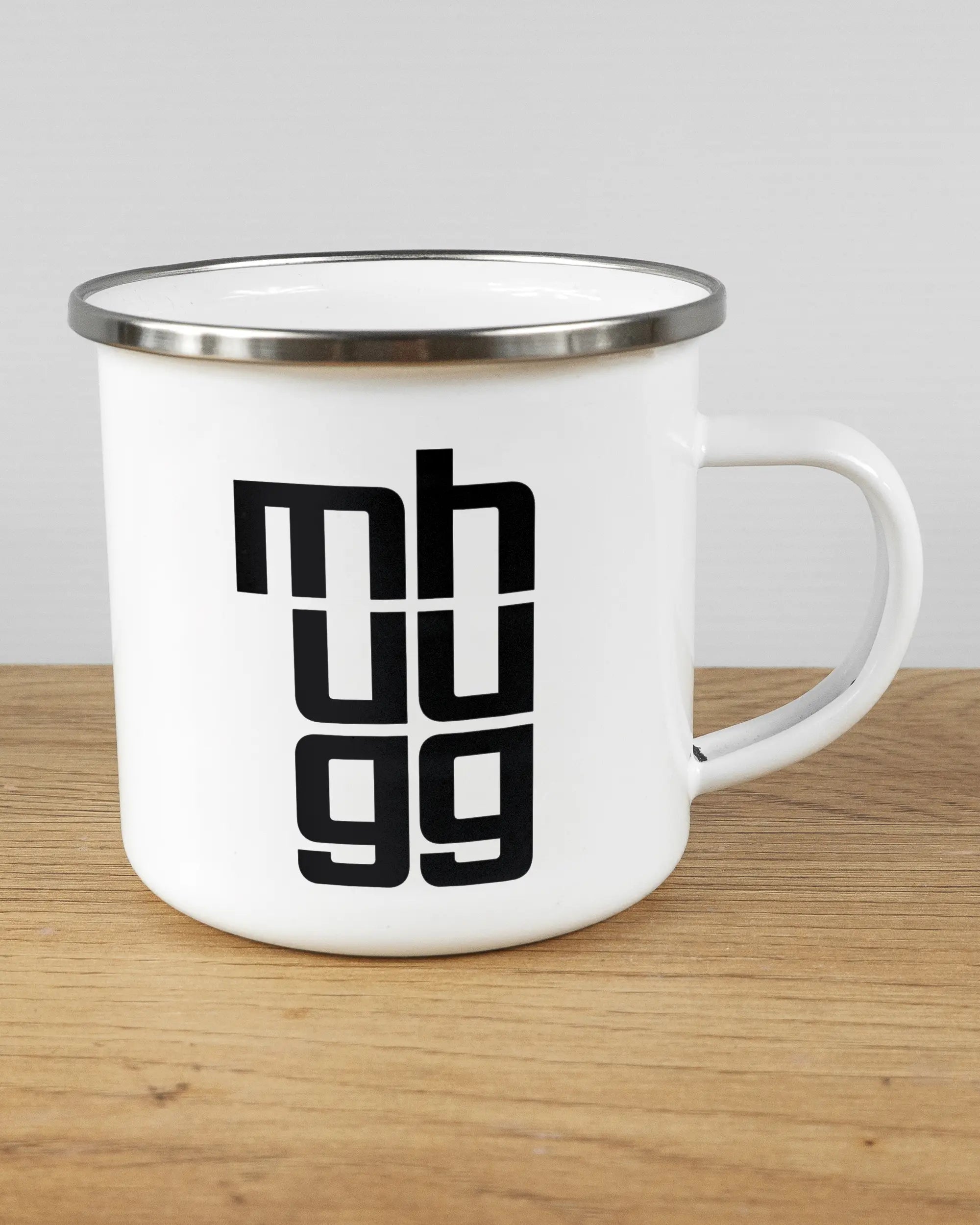 Alternativbild, das die rechte Seite der beidseitig bedruckten Emailletasse von Maondo mit dem Design Hug Mug in der Farbe White-Silver auf einem Holztisch zeigt