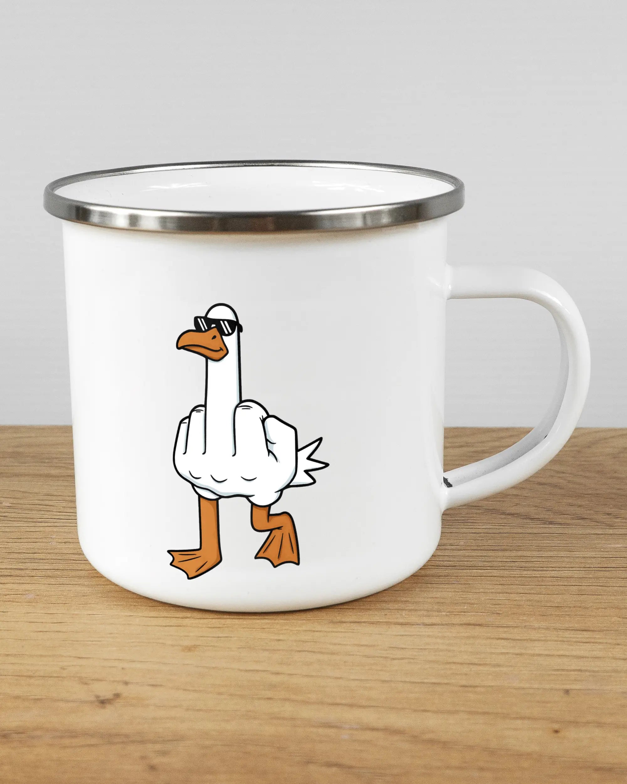 Alternativbild, das die rechte Seite der beidseitig bedruckten Emailletasse von Maondo mit dem Design I give a duck in der Farbe White-Silver auf einem Holztisch zeigt