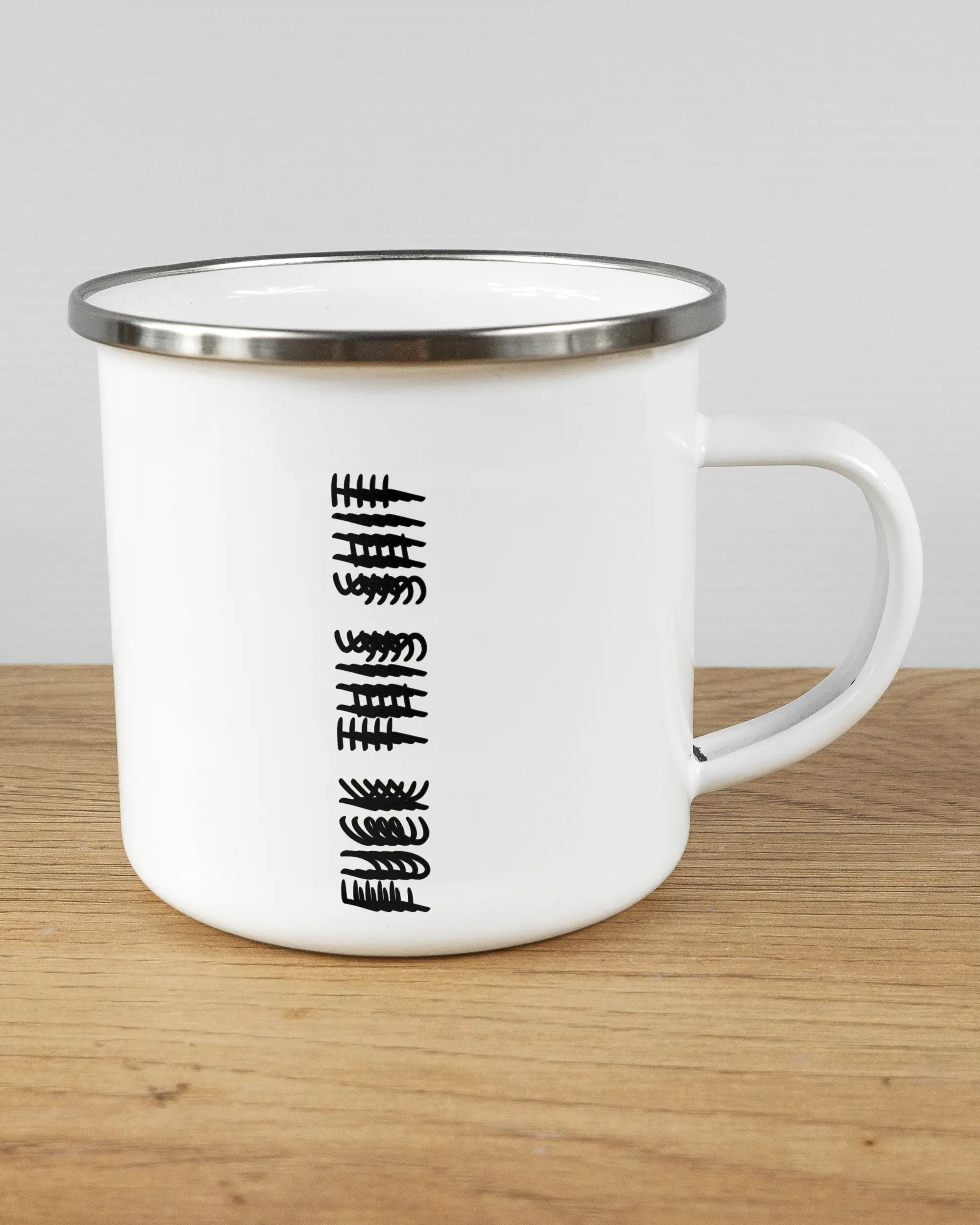 Alternativbild, das die rechte Seite der beidseitig bedruckten Emailletasse von Maondo mit dem Design Hidden Message in der Farbe White-Silver auf einem Holztisch zeigt