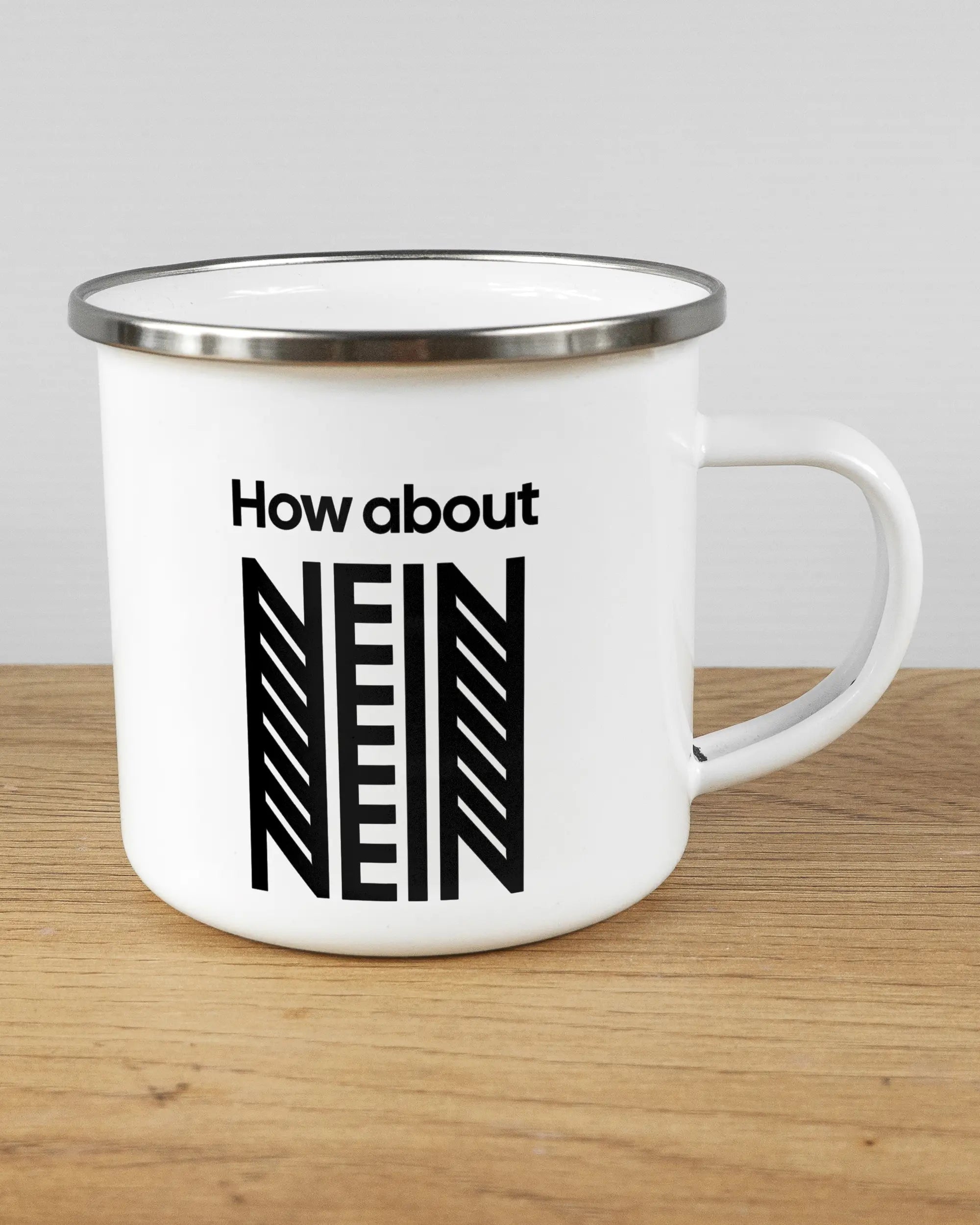 Alternativbild, das die rechte Seite der beidseitig bedruckten Emailletasse von Maondo mit dem Design How about nein in der Farbe White-Silver auf einem Holztisch zeigt