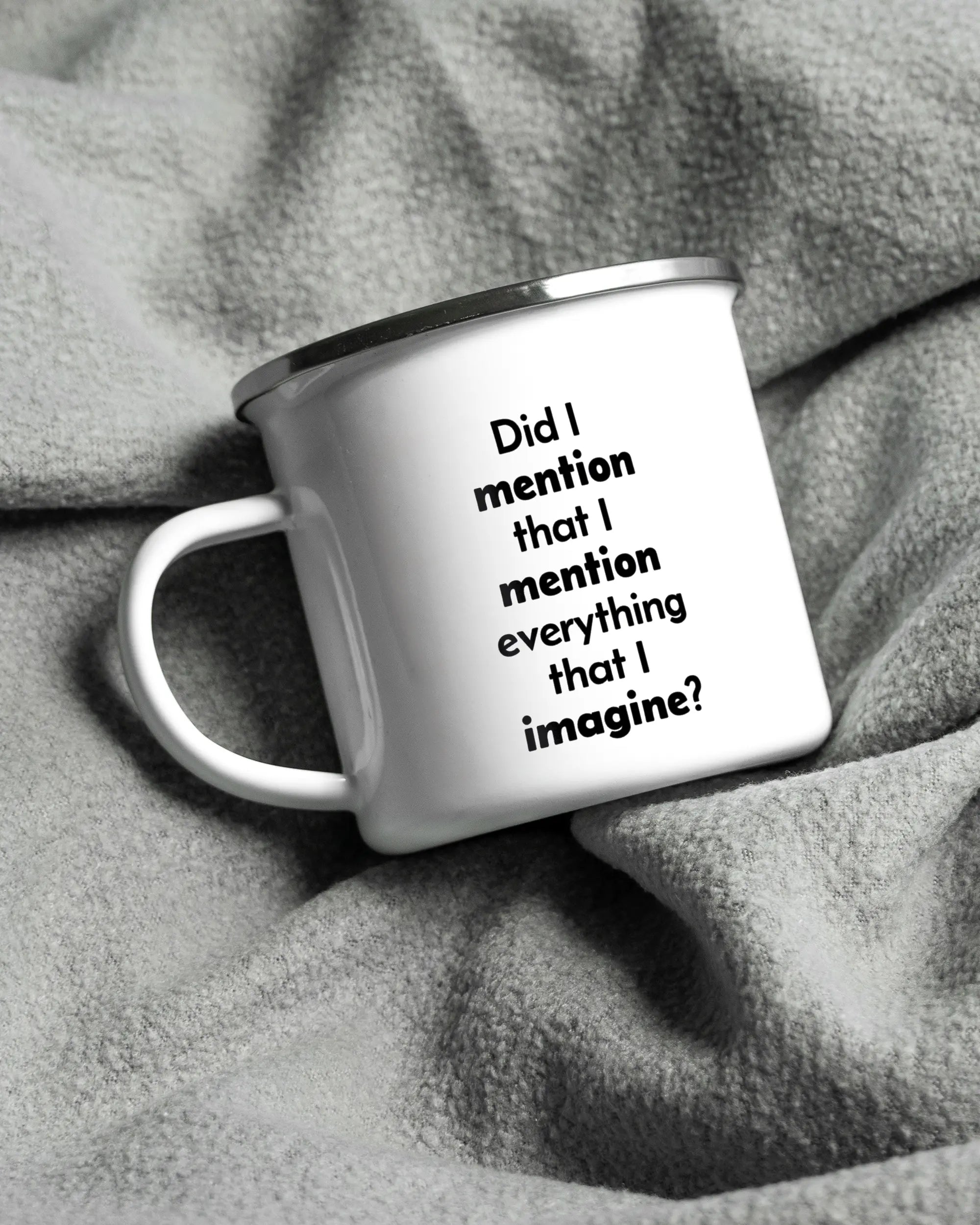 Aufnahme, die die linke Seite der beidseitig bedruckten Emailletasse von Maondo auf einer flauschigen Fließdecke mit dem Design White-Silver in der Farbe  zeigt