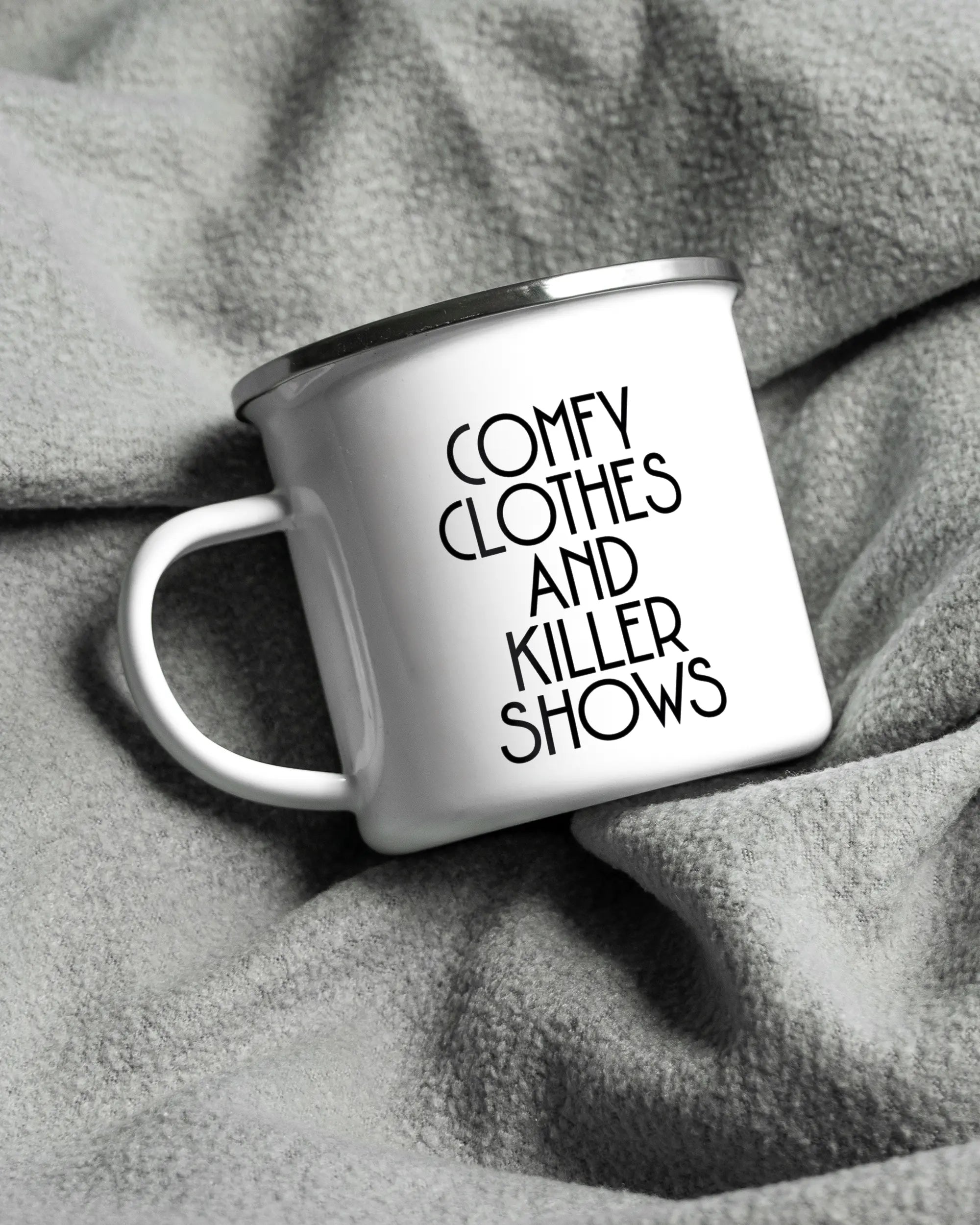 Aufnahme, die die linke Seite der beidseitig bedruckten Emailletasse von Maondo auf einer flauschigen Fließdecke mit dem Design White-Silver in der Farbe  zeigt