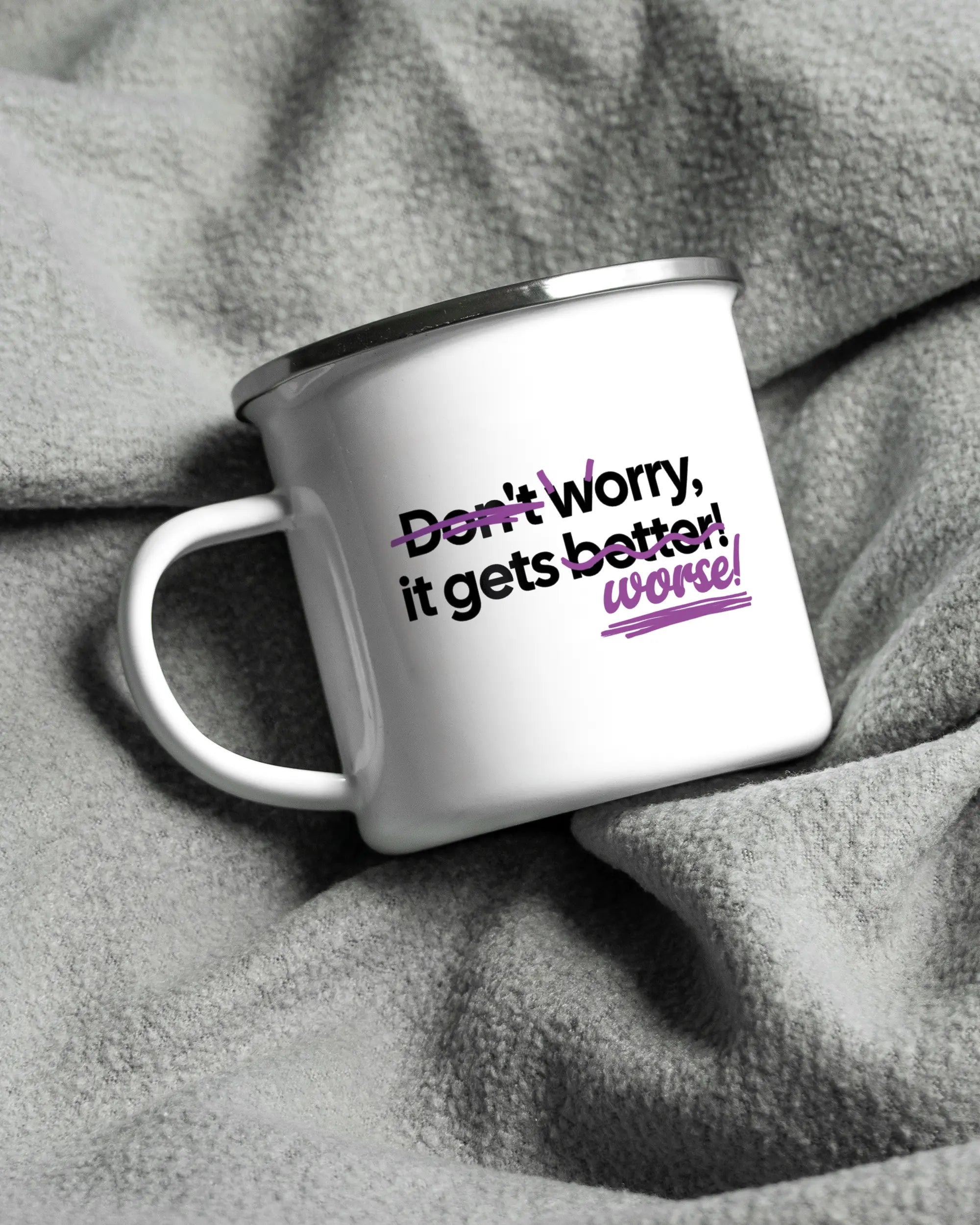 Aufnahme, die die linke Seite der beidseitig bedruckten Emailletasse von Maondo auf einer flauschigen Fließdecke mit dem Design White-Silver in der Farbe  zeigt