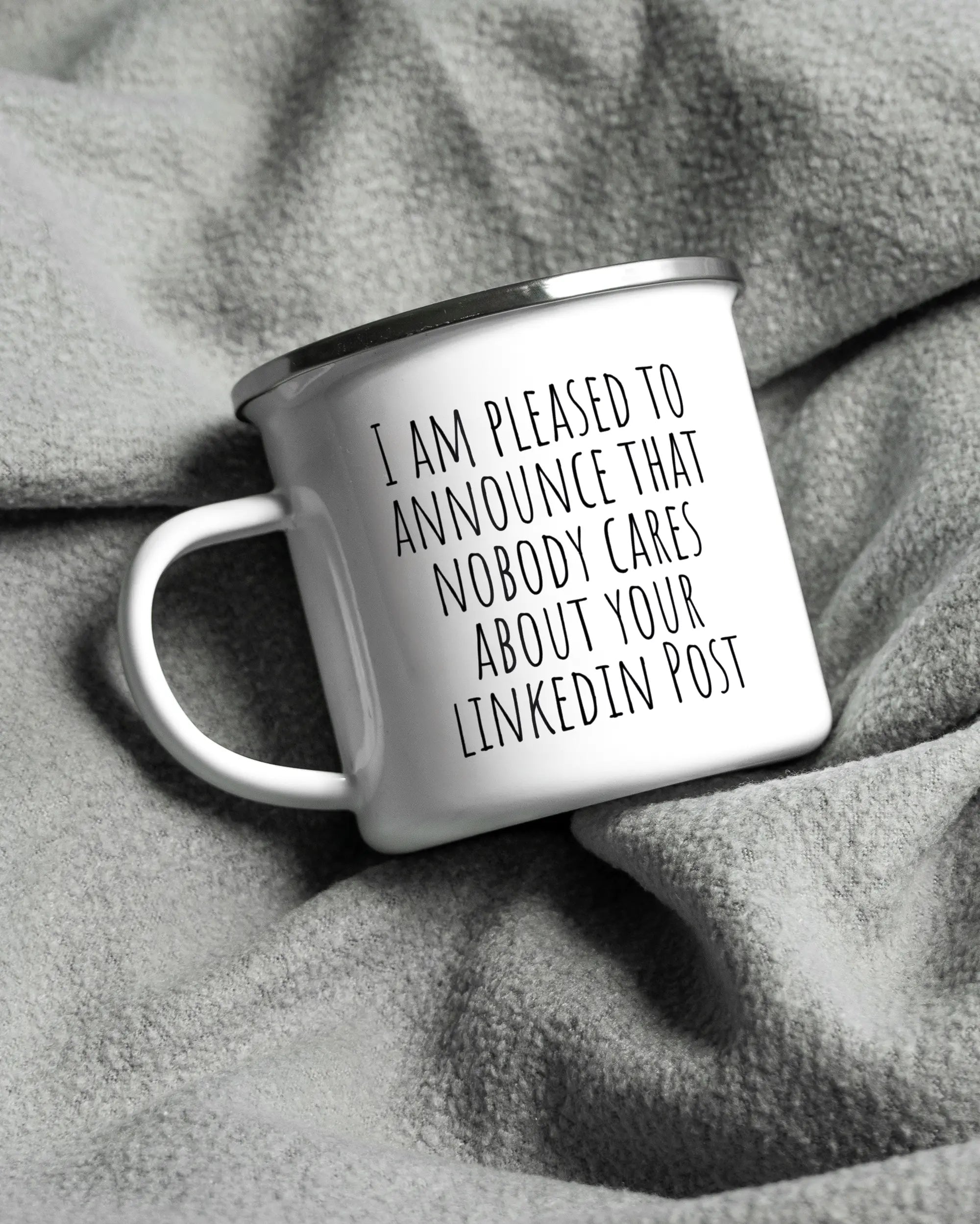 Aufnahme, die die linke Seite der beidseitig bedruckten Emailletasse von Maondo auf einer flauschigen Fließdecke mit dem Design White-Silver in der Farbe  zeigt