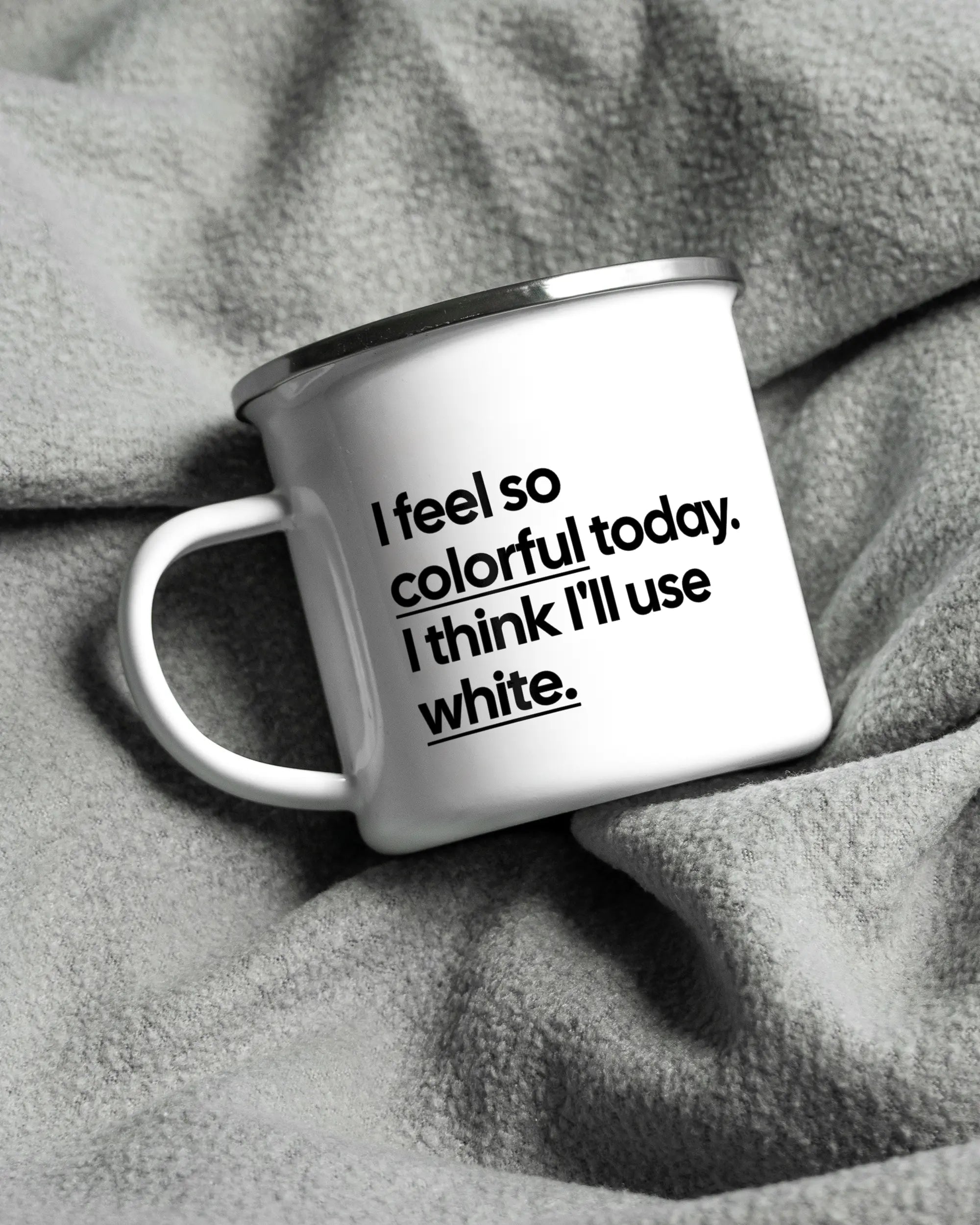 Aufnahme, die die linke Seite der beidseitig bedruckten Emailletasse von Maondo auf einer flauschigen Fließdecke mit dem Design White-Silver in der Farbe  zeigt