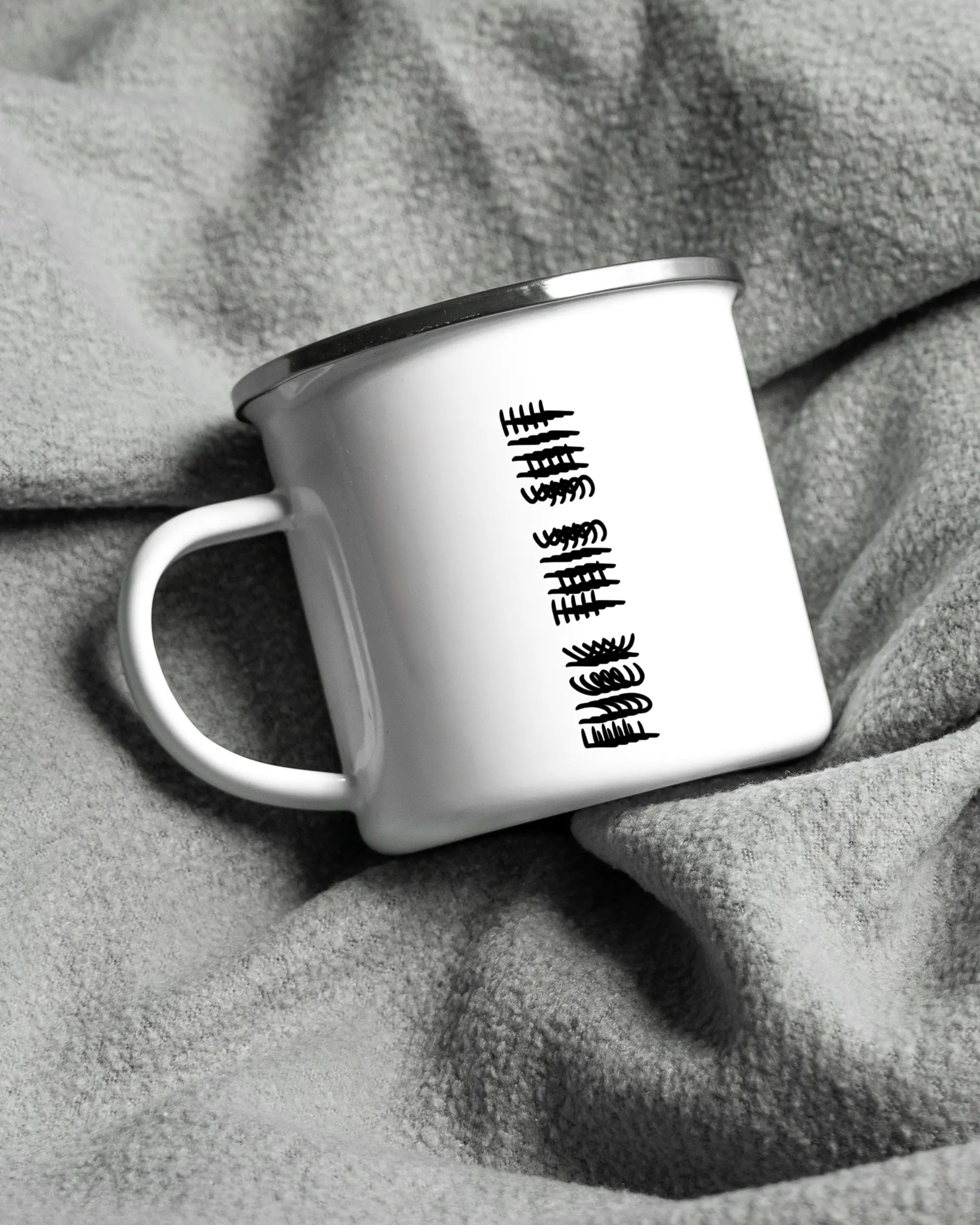 Aufnahme, die die linke Seite der beidseitig bedruckten Emailletasse von Maondo auf einer flauschigen Fließdecke mit dem Design White-Silver in der Farbe  zeigt