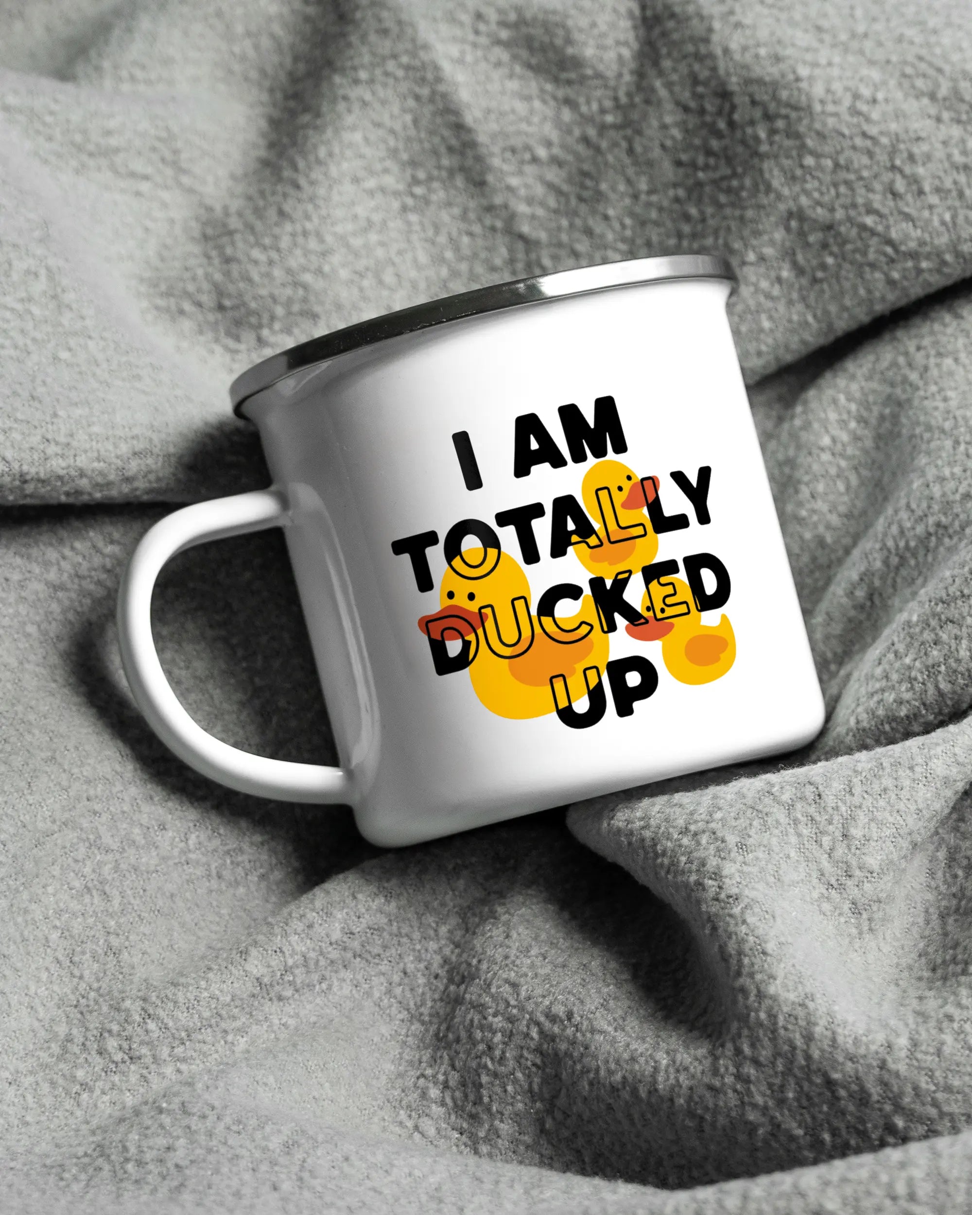 Aufnahme, die die linke Seite der beidseitig bedruckten Emailletasse von Maondo auf einer flauschigen Fließdecke mit dem Design White-Silver in der Farbe  zeigt