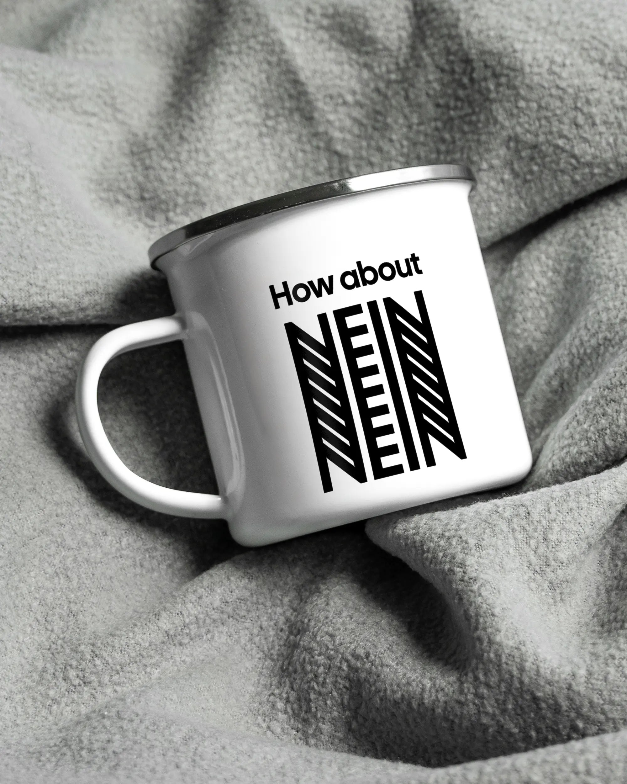 Aufnahme, die die linke Seite der beidseitig bedruckten Emailletasse von Maondo auf einer flauschigen Fließdecke mit dem Design White-Silver in der Farbe  zeigt