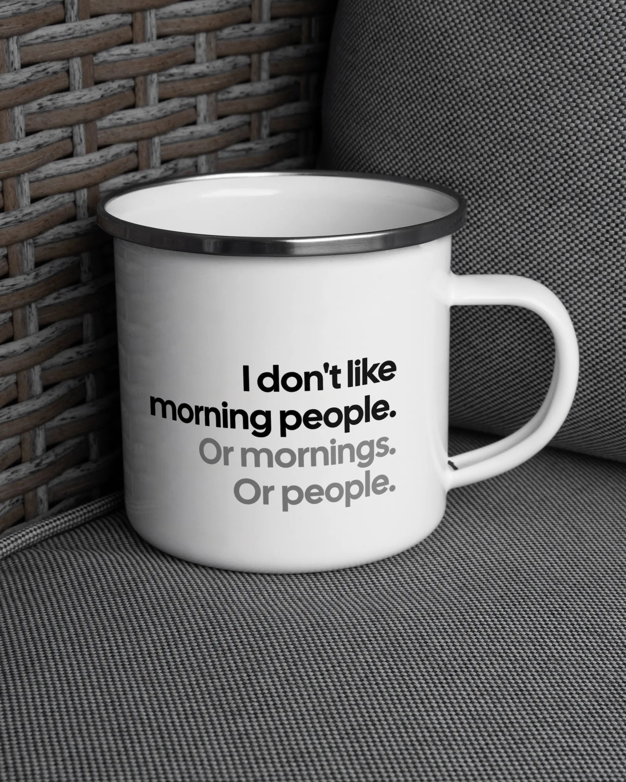 Ansicht der rechten Seite der beidseitig bedruckten Emailletasse von Maondo auf einem Balkonmöbel bzw. Campingstuhl mit dem Design White-Silver in der Farbe 