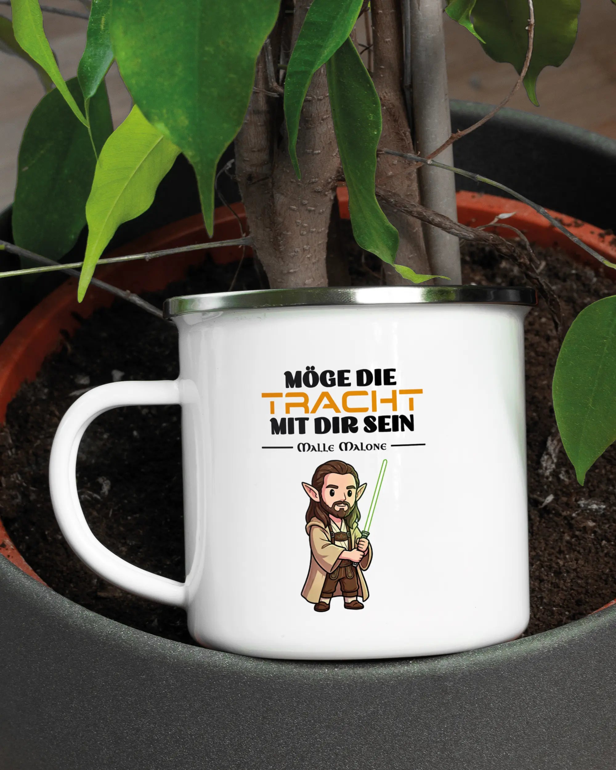 Aufnahme der linken Seite der beidseitig bedruckten Emailletasse von Maondo mit dem Design Tracht mit dir in der Farbe White-Silver in einem Blumentopf