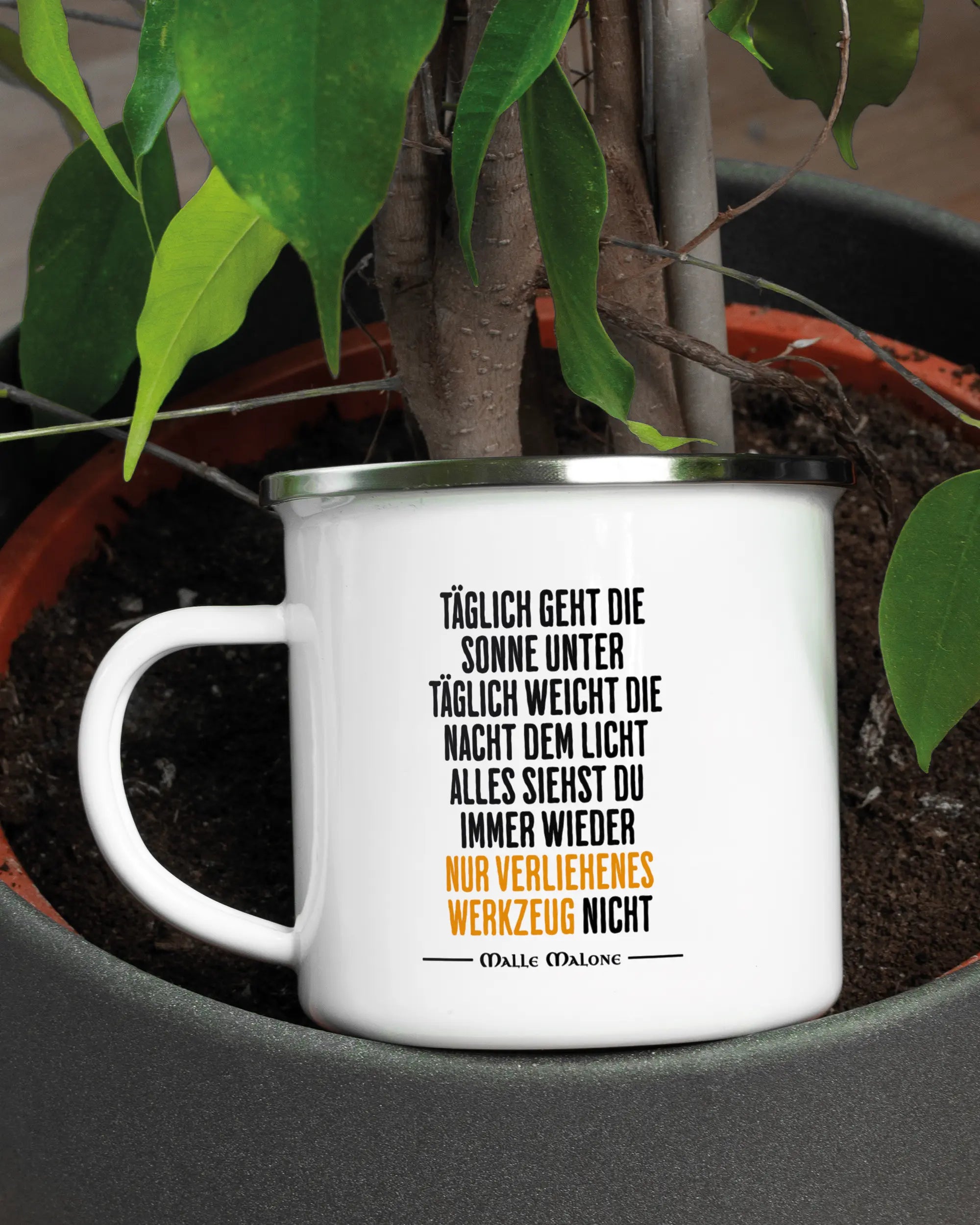 Aufnahme der linken Seite der beidseitig bedruckten Emailletasse von Maondo mit dem Design Wegzeug in der Farbe White-Silver in einem Blumentopf
