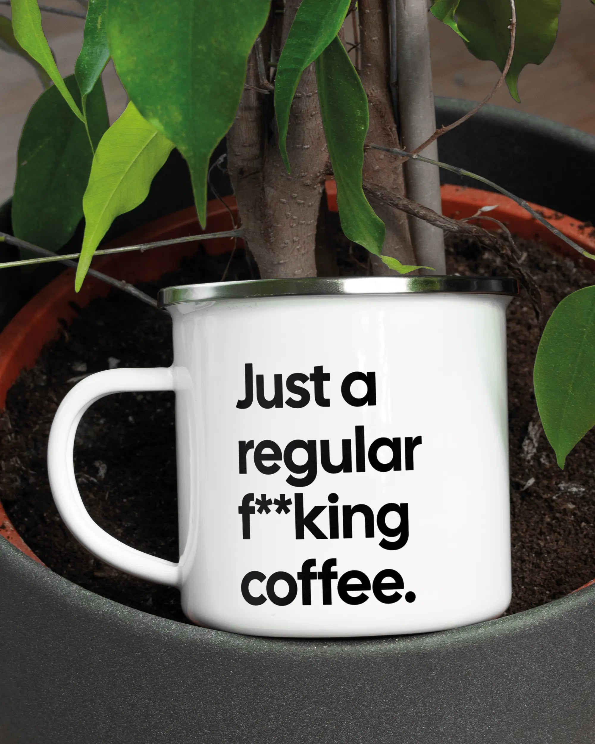 Aufnahme der linken Seite der beidseitig bedruckten Emailletasse von Maondo mit dem Design Regular Coffee in der Farbe White-Silver in einem Blumentopf