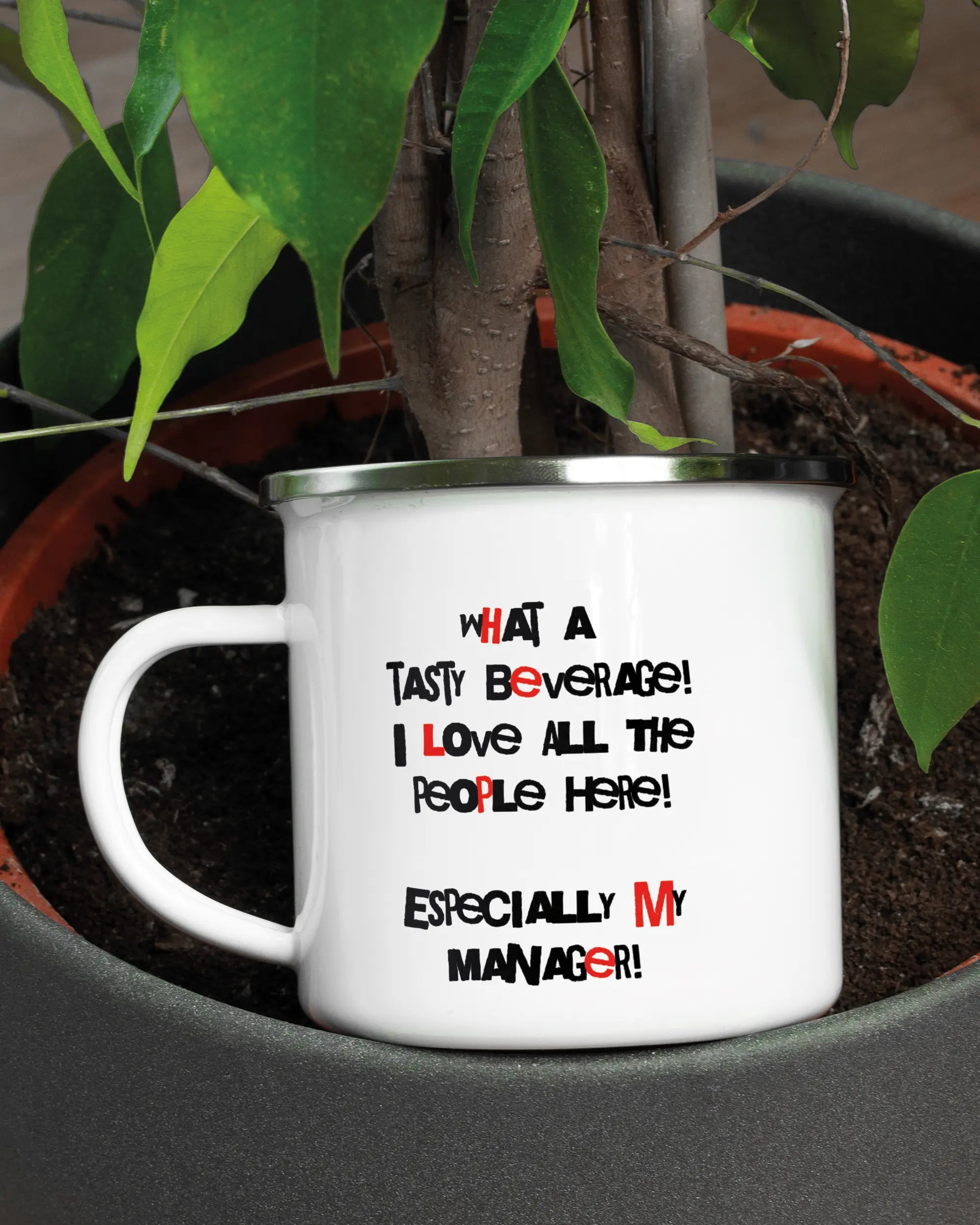 Aufnahme der linken Seite der beidseitig bedruckten Emailletasse von Maondo mit dem Design Help me in der Farbe White-Silver in einem Blumentopf