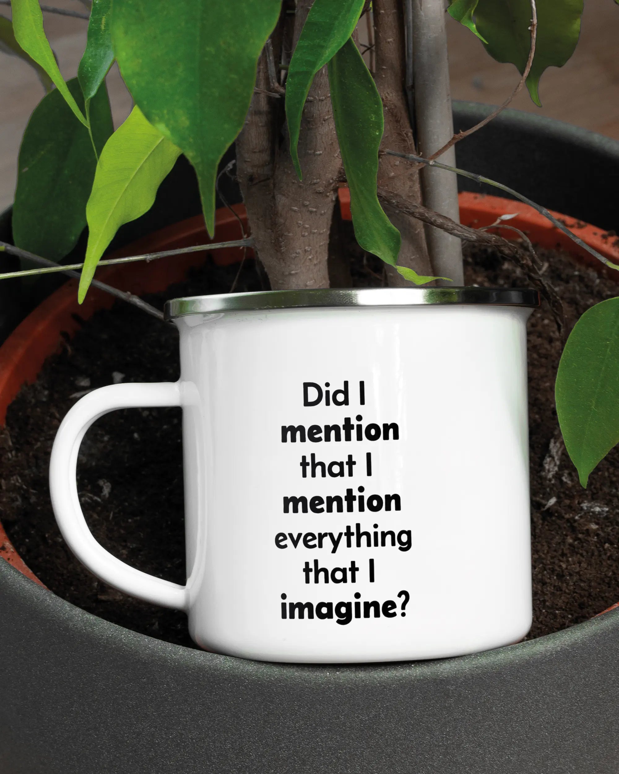 Aufnahme der linken Seite der beidseitig bedruckten Emailletasse von Maondo mit dem Design Did I mention in der Farbe White-Silver in einem Blumentopf