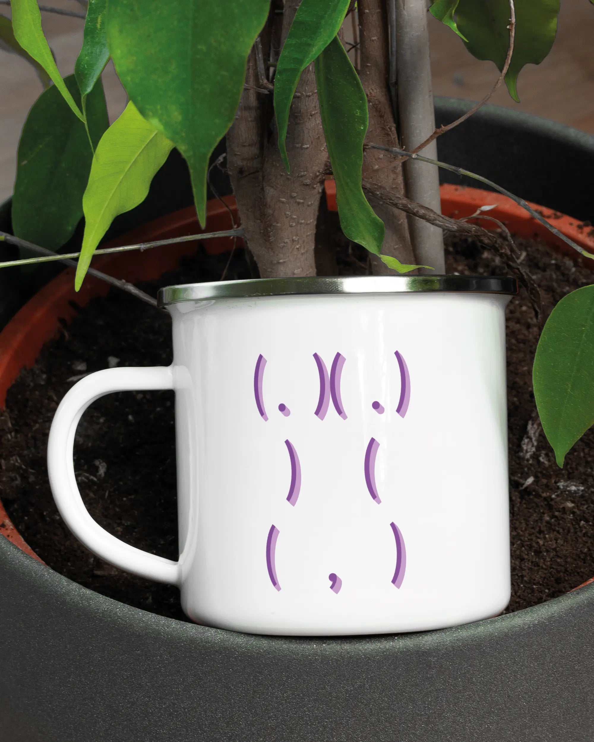 Aufnahme der linken Seite der beidseitig bedruckten Emailletasse von Maondo mit dem Design Body Language in der Farbe White-Silver in einem Blumentopf