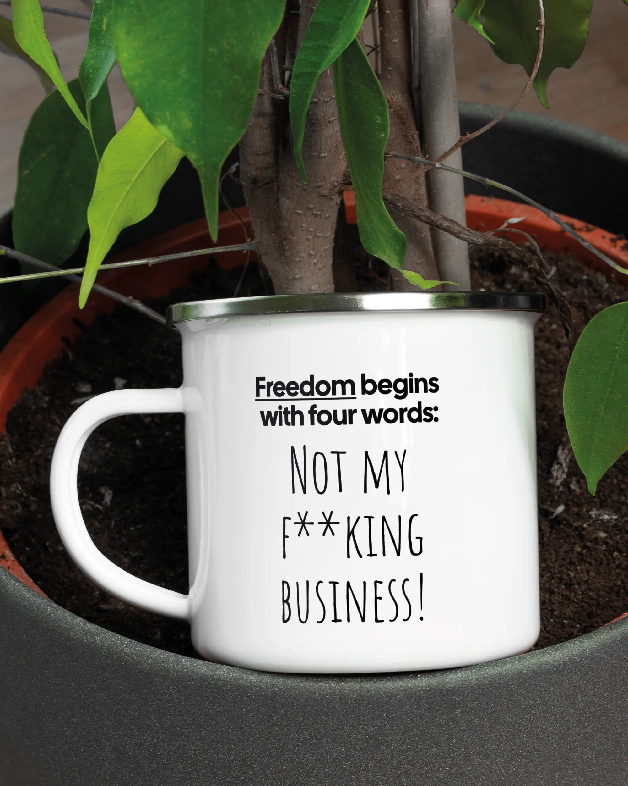 Aufnahme der linken Seite der beidseitig bedruckten Emailletasse von Maondo mit dem Design 4 Freedom in der Farbe White-Silver in einem Blumentopf