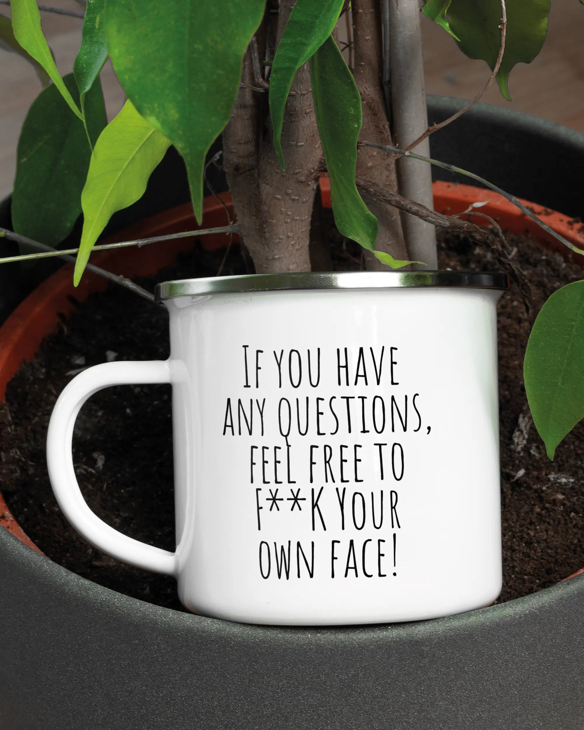 Aufnahme der linken Seite der beidseitig bedruckten Emailletasse von Maondo mit dem Design Feel Free in der Farbe White-Silver in einem Blumentopf