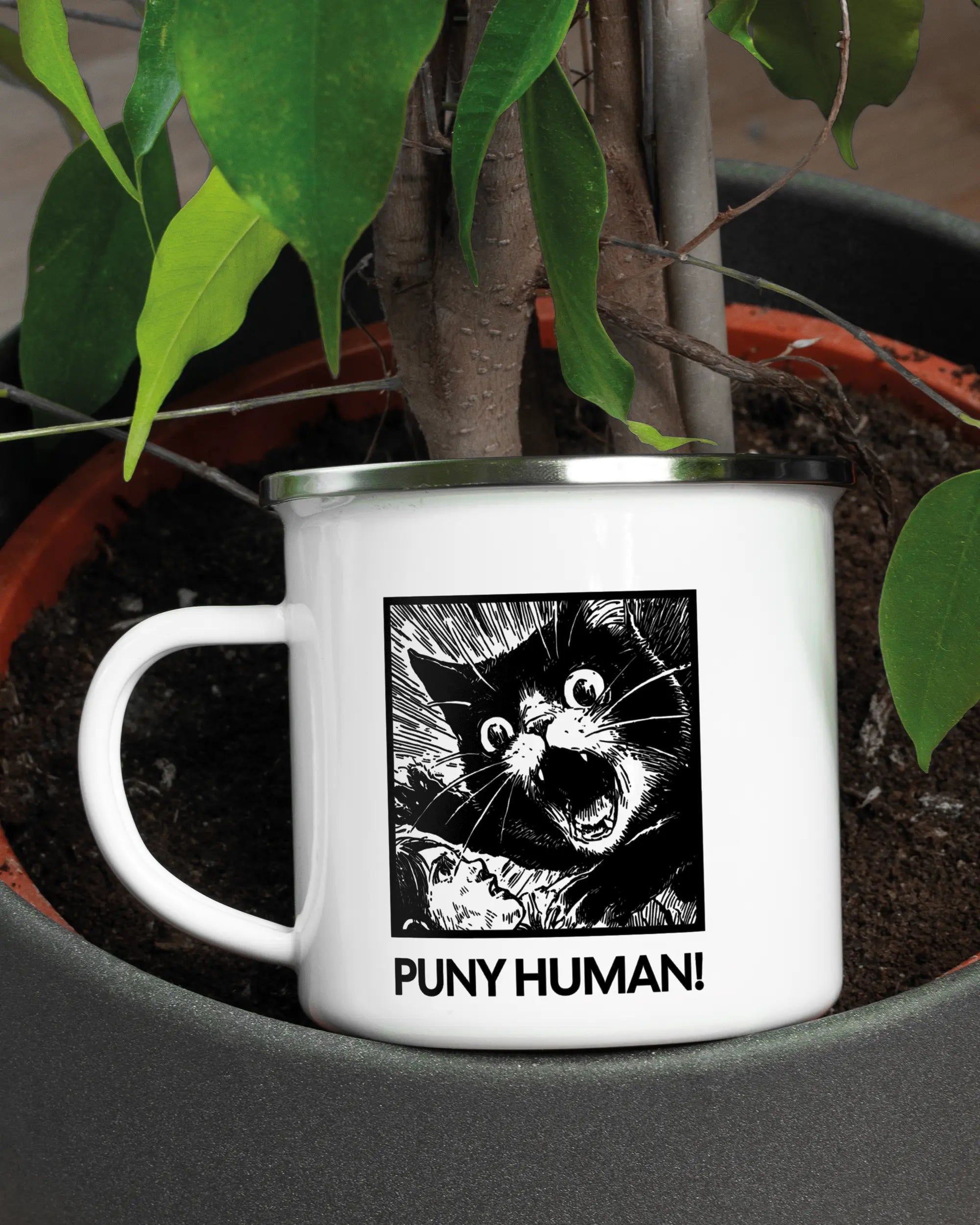 Aufnahme der linken Seite der beidseitig bedruckten Emailletasse von Maondo mit dem Design Puny Human in der Farbe White-Silver in einem Blumentopf