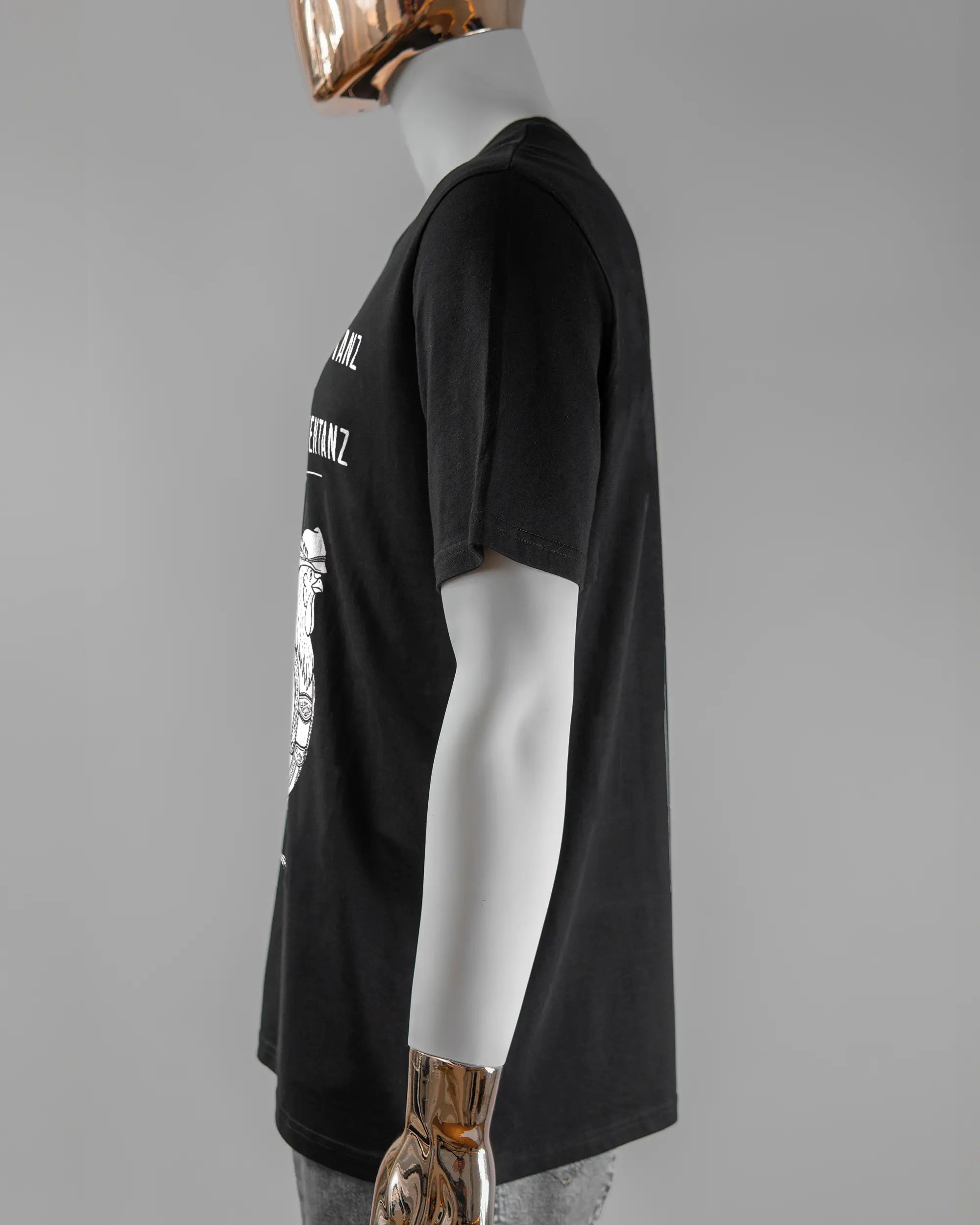 Seitenansicht des Organic Unisex T-Shirt Casual von Maondo mit dem Design Trachtentanz vorne in der Farbe Black und in der Größe L getragen von einer maskulinen Puppe