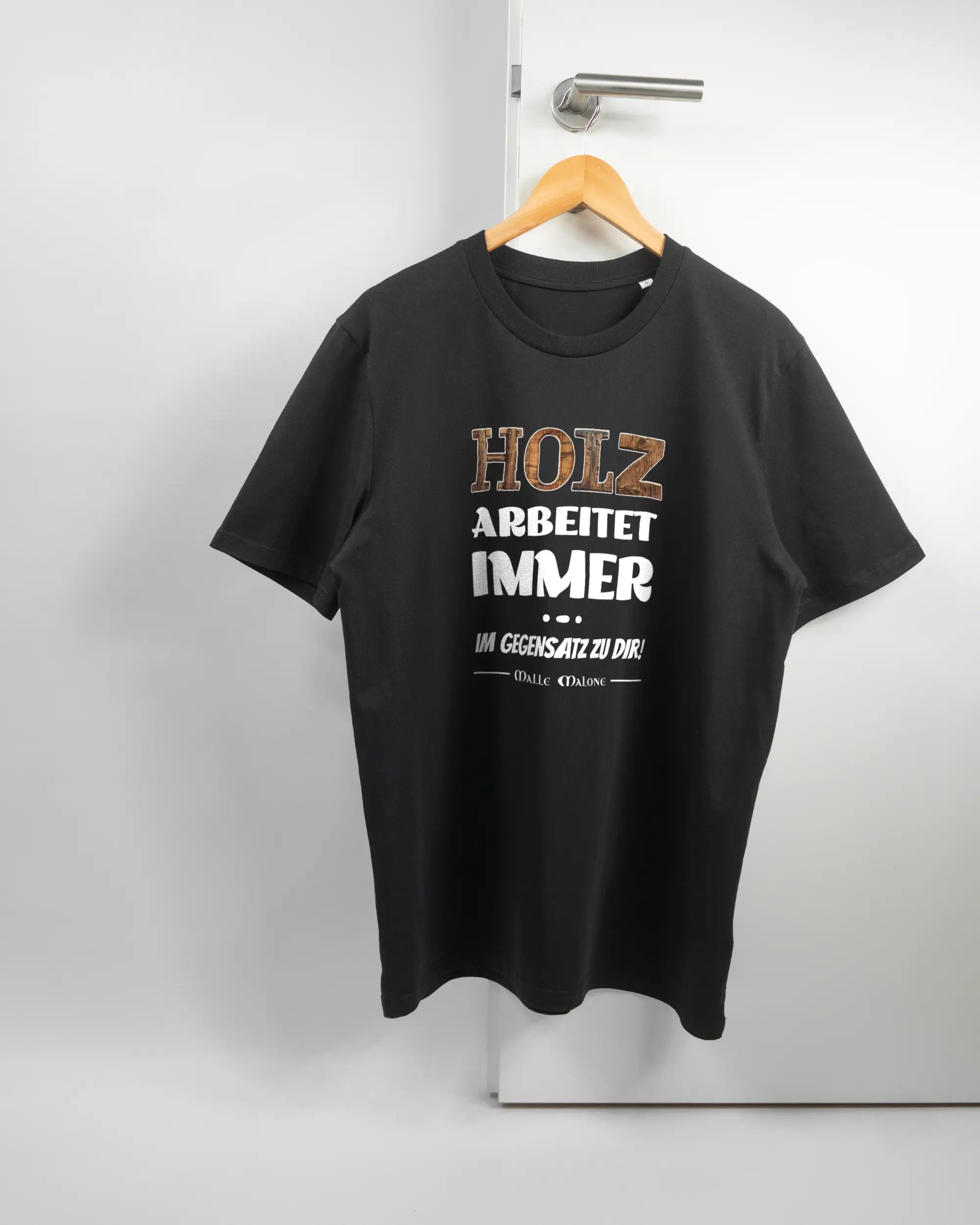 Vorderseite des Organic Unisex T-Shirt Casual von Maondo mit dem Design Holzarbeit in der Farbe Black und in der Größe L auf einem Bügel an der Türklinke aufgehängt