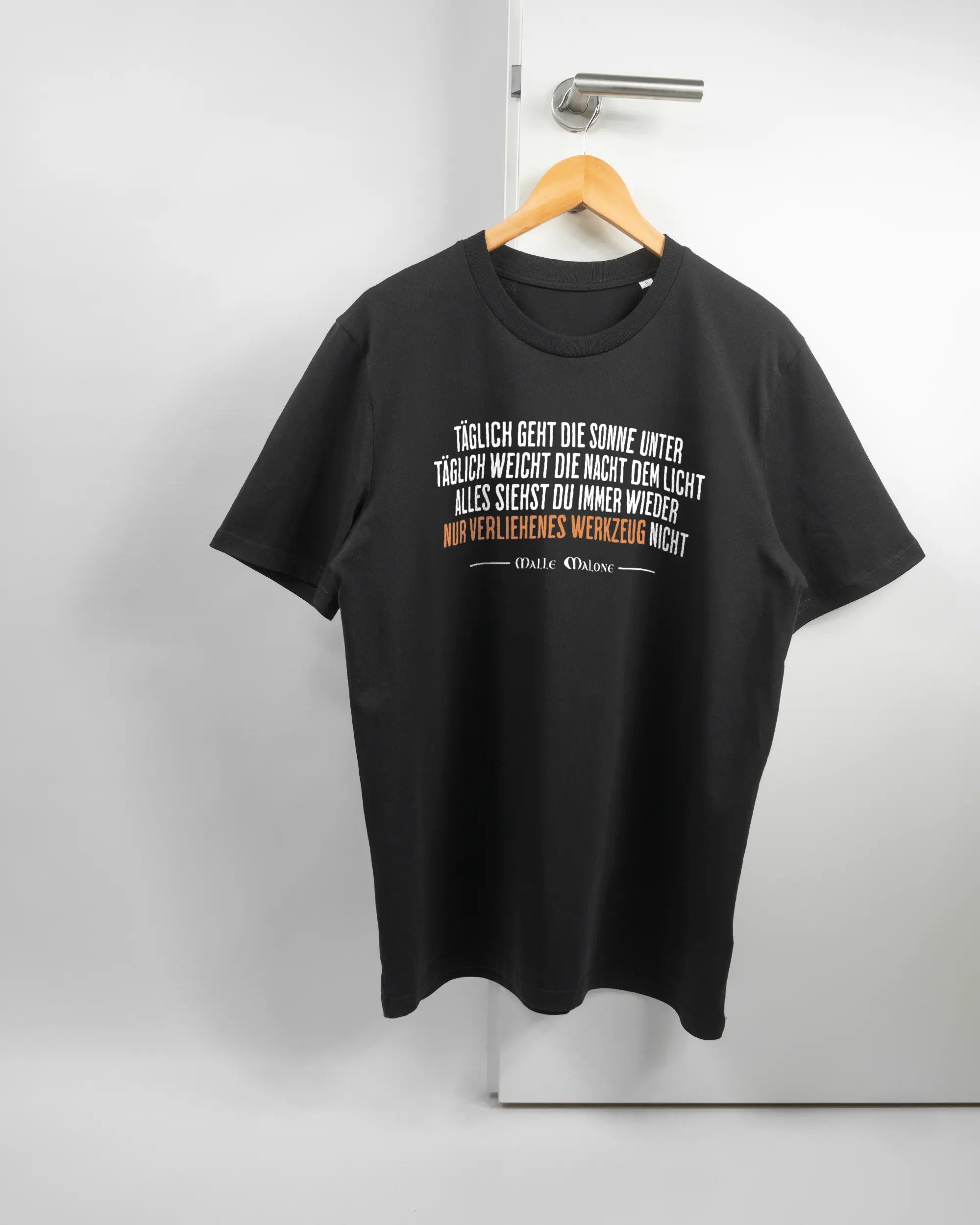 Vorderseite des Organic Unisex T-Shirt Casual von Maondo mit dem Design Wegzeug in der Farbe Black und in der Größe L auf einem Bügel an der Türklinke aufgehängt