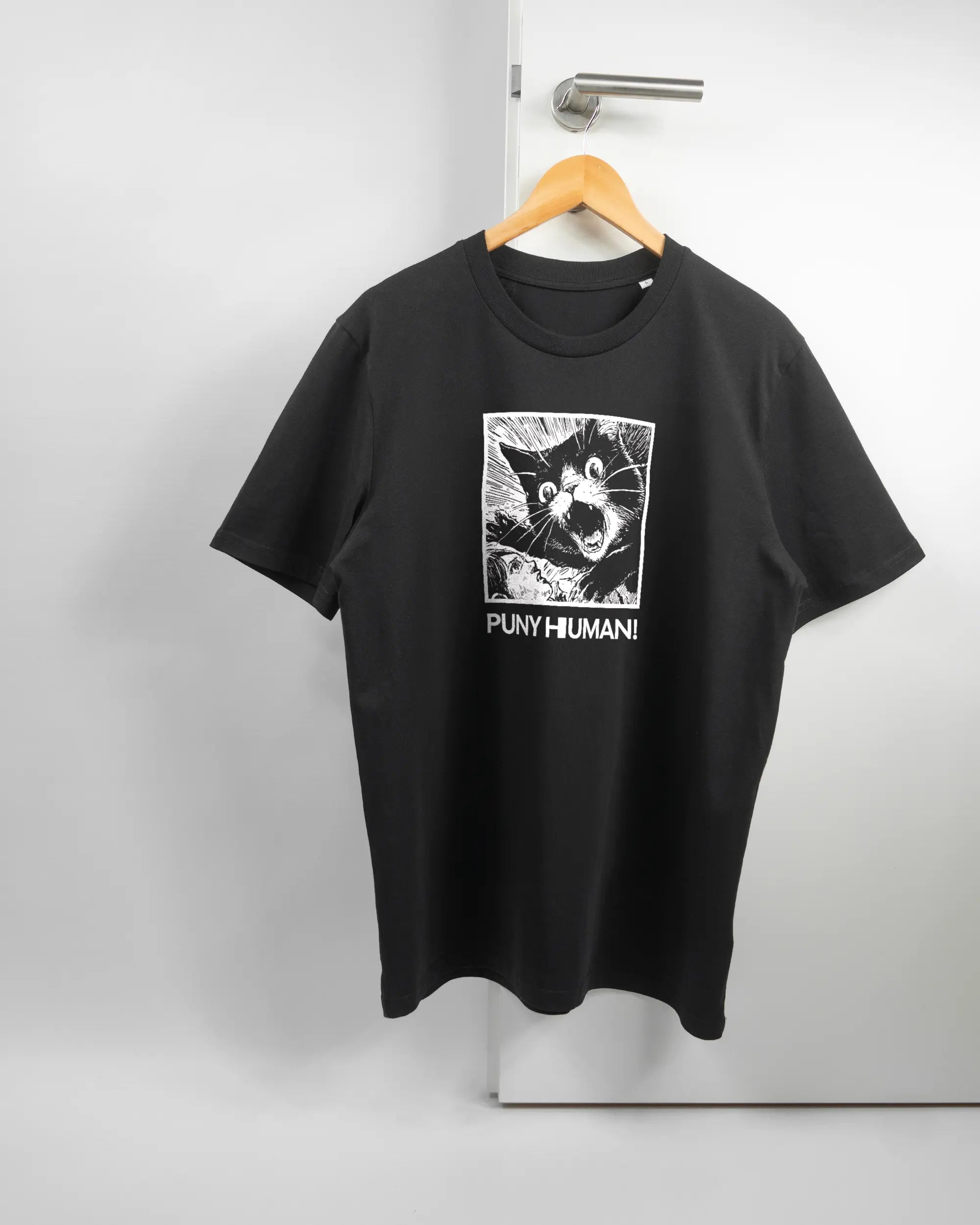Vorderseite des Organic Unisex T-Shirt Casual von Maondo mit dem Design Puny Human in der Farbe Black und in der Größe L auf einem Bügel an der Türklinke aufgehängt
