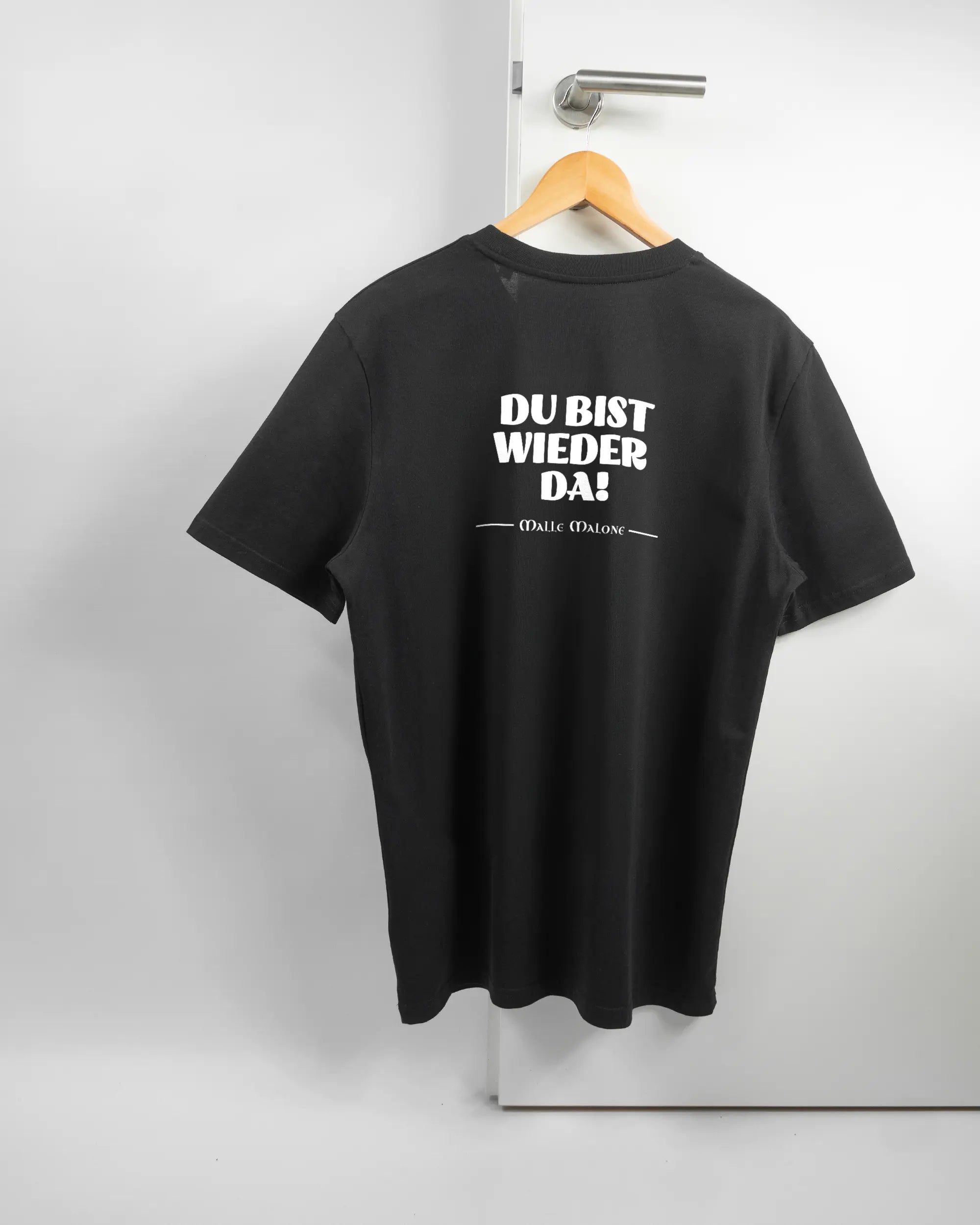 Rückseite des Organic Unisex T-Shirt Casual von Maondo mit dem Design Wieder da in der Farbe Black und in der Größe L auf einem Bügel an der Türklinke aufgehängt