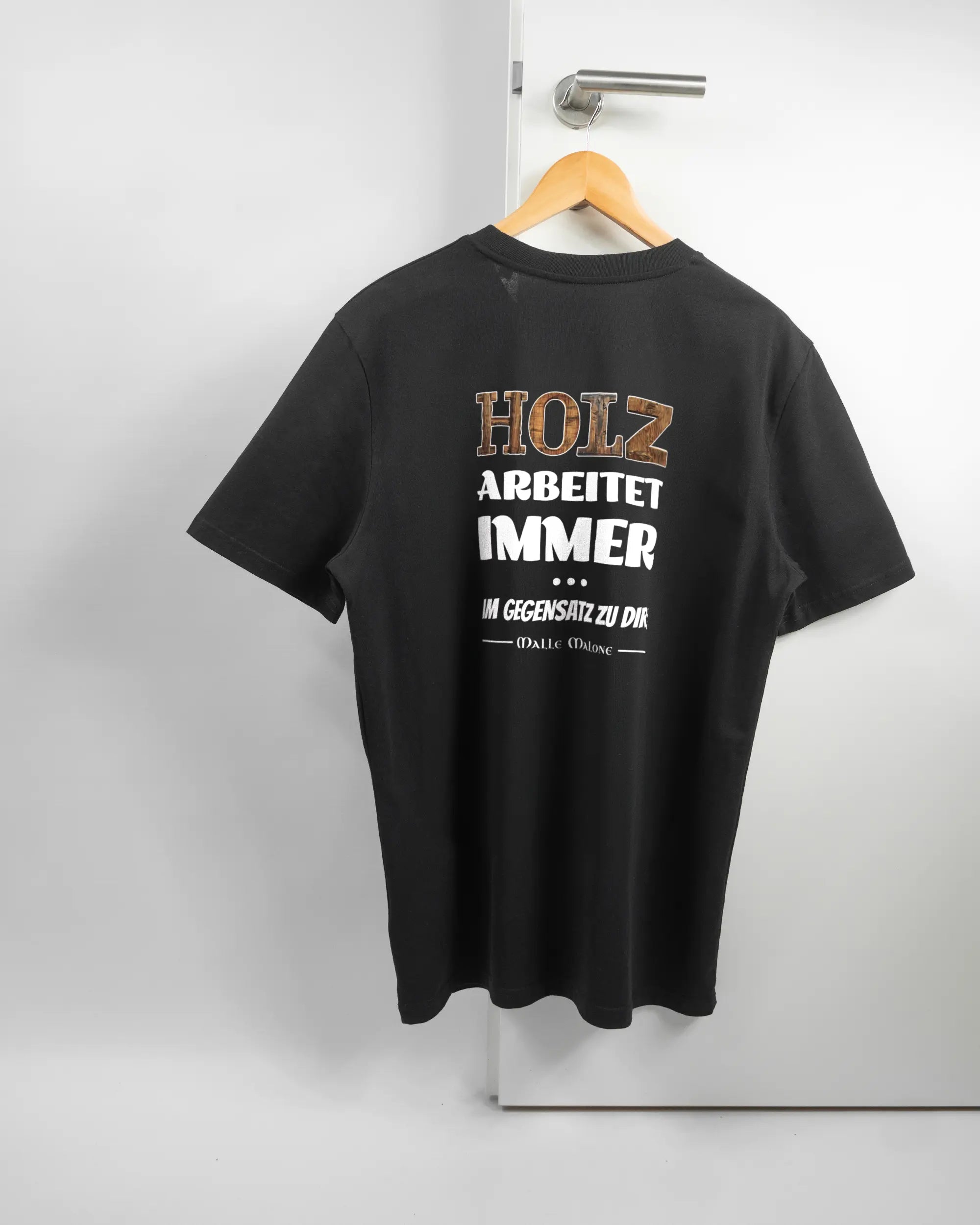 Rückseite des Organic Unisex T-Shirt Casual von Maondo mit dem Design Holzarbeit in der Farbe Black und in der Größe L auf einem Bügel an der Türklinke aufgehängt
