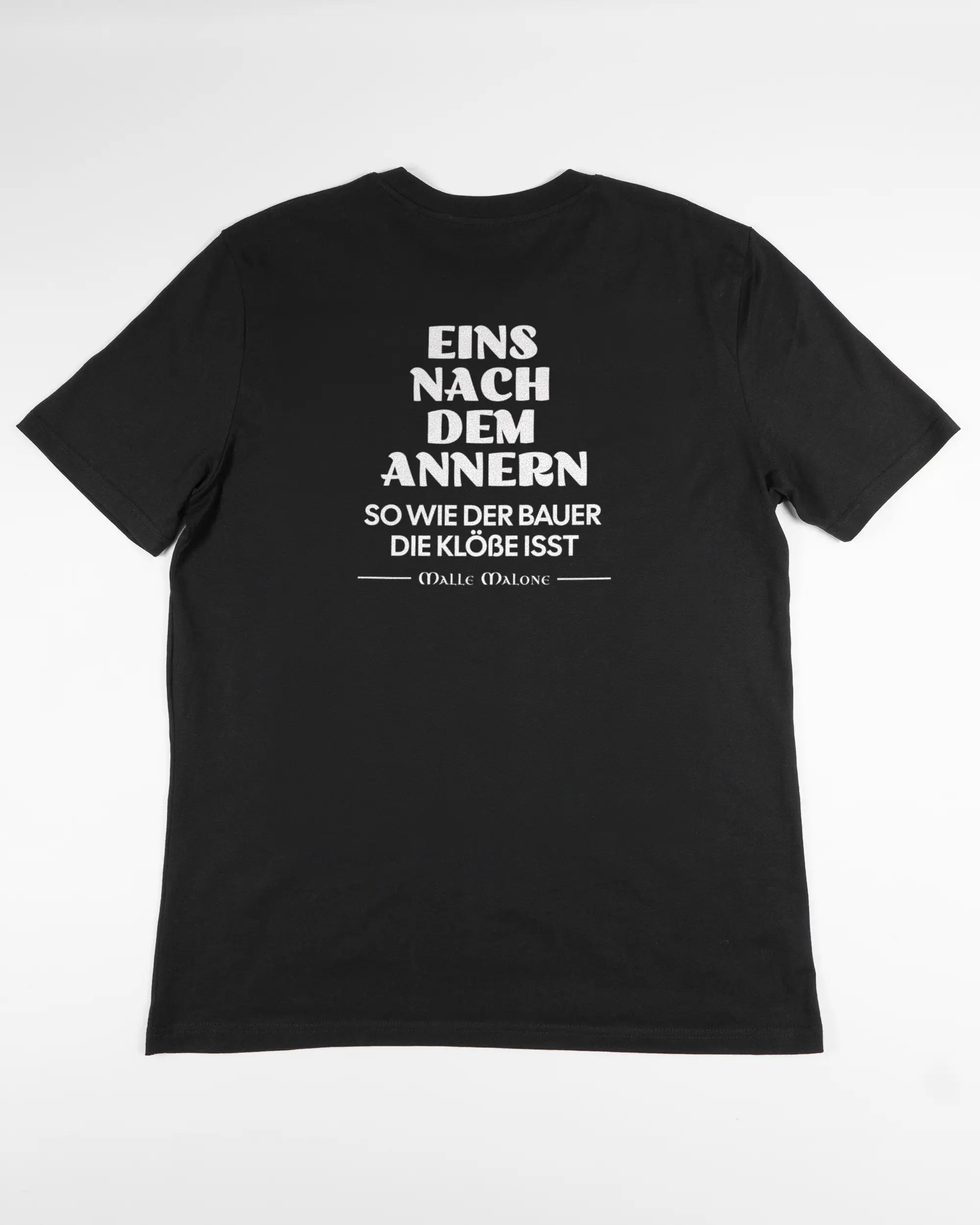 Rückseite des Organic Unisex T-Shirt Casual von Maondo mit dem Design Eins nach dem Annern in der Farbe Black und in der Größe L flach auf den Boden gelegt