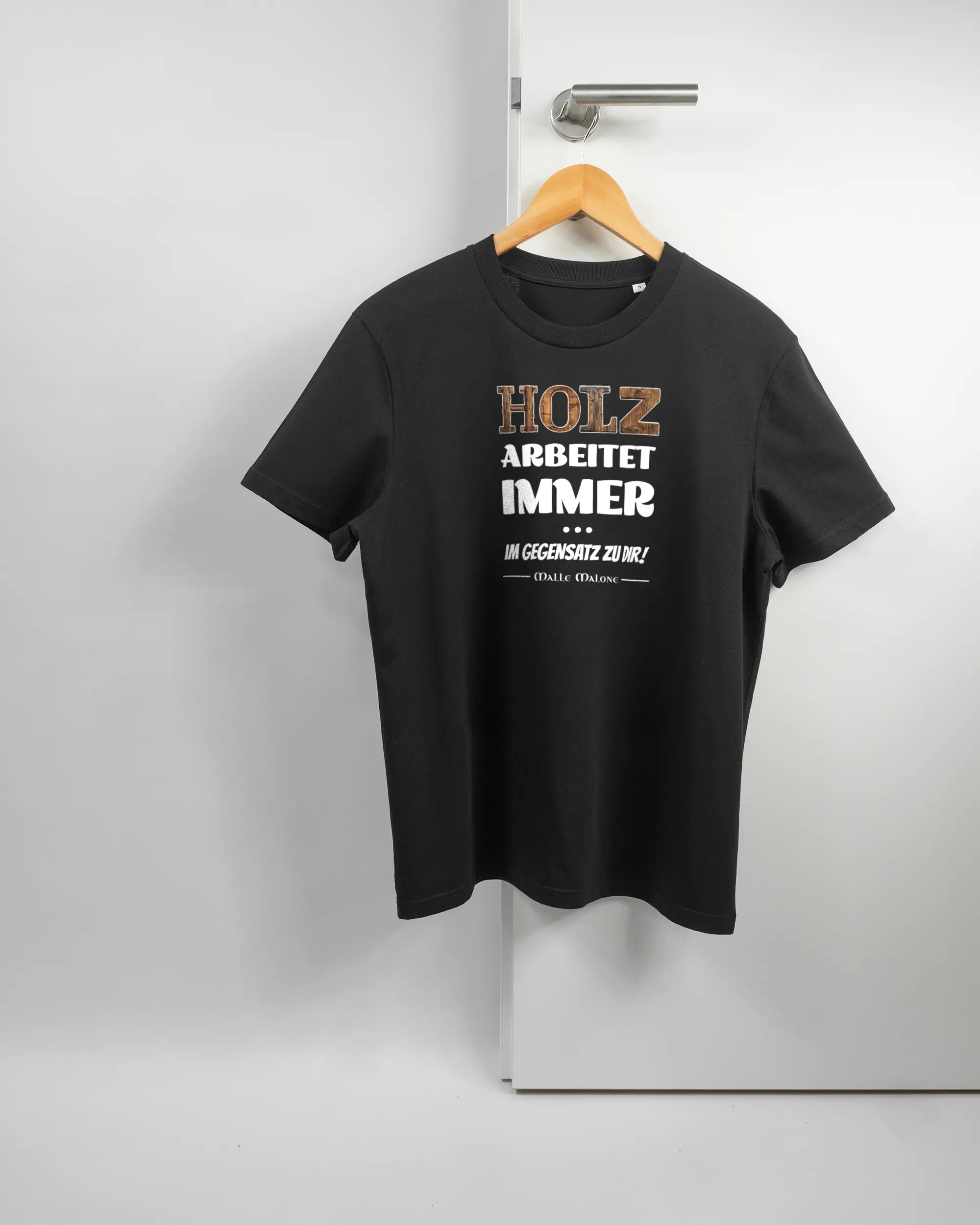 Vorderseite des Organic Unisex T-Shirt Casual von Maondo mit dem Design Holzarbeit in der Farbe Black und in der Größe S auf einem Bügel an der Türklinke aufgehängt
